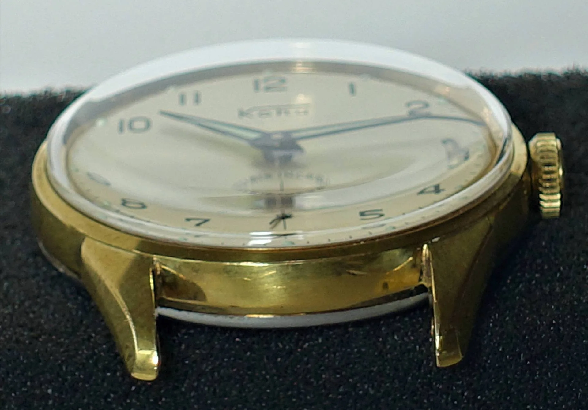 Goldfarbene Armbanduhr mit hellem Zifferblatt und schwarzen Zahlen.