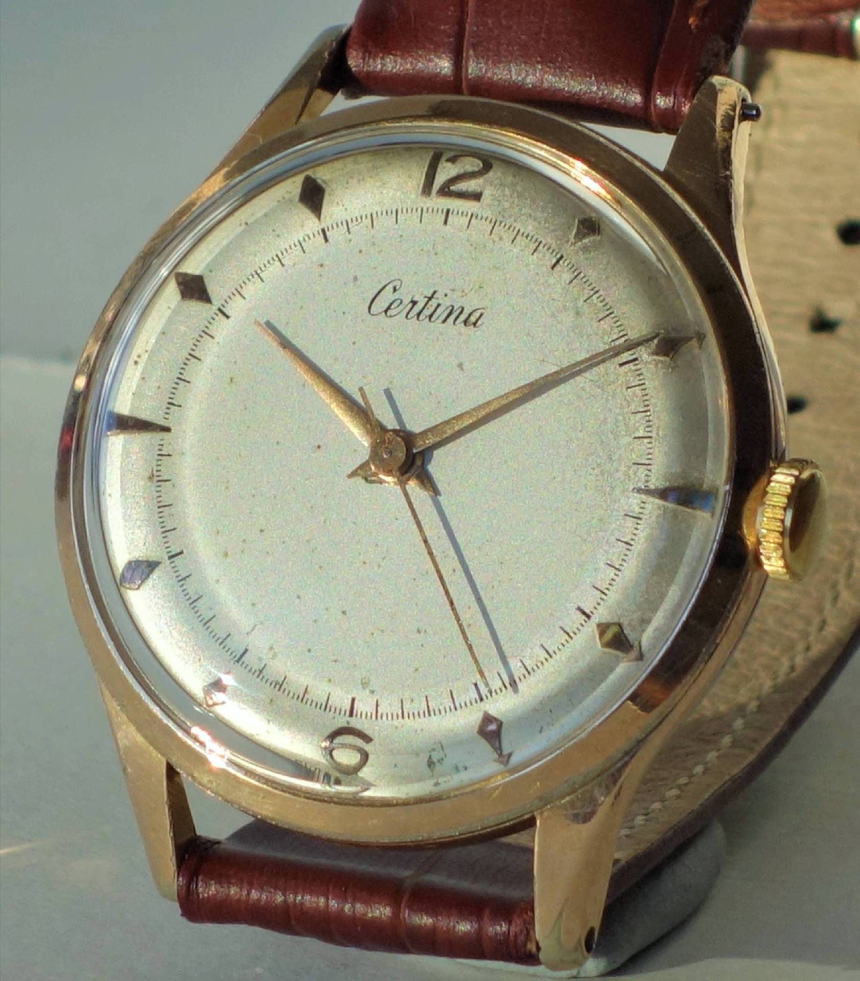 Klassische Armbanduhr mit goldfarbenem Gehäuse, hellem Zifferblatt und braunem Lederarmband.