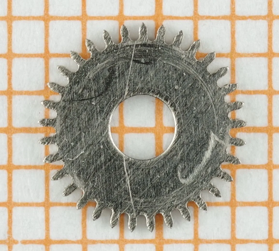 Uhrwerk Zahnrad Metall Rundes Zahnrad aus Metall für Uhrwerke, mit zentraler Öffnung und feinen Zähnen.