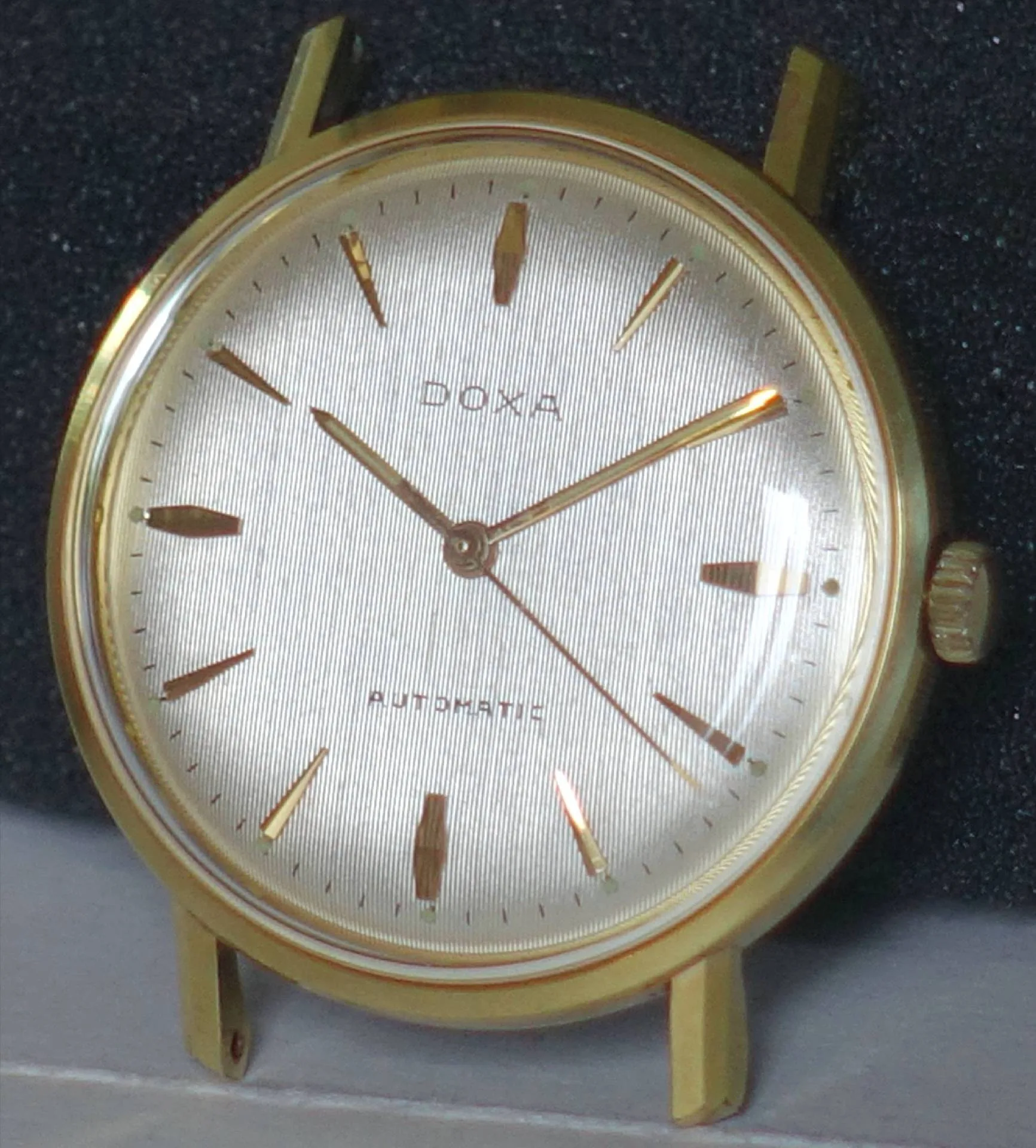 Goldfarbene Doxa Armbanduhr mit hellem Zifferblatt und goldenen Indizes.