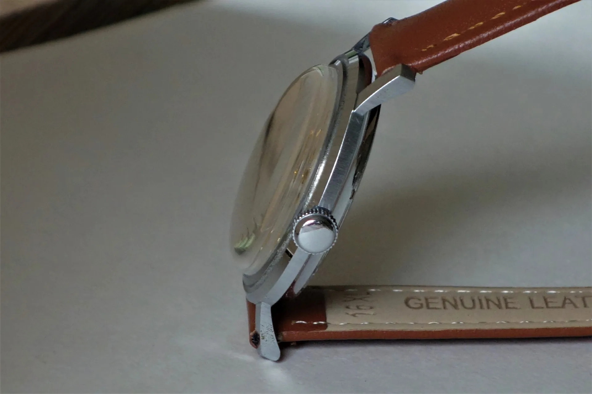 Uhr mit braunem Armband Armbanduhr mit silberfarbenem Gehäuse und braunem Lederarmband in Seitenansicht.