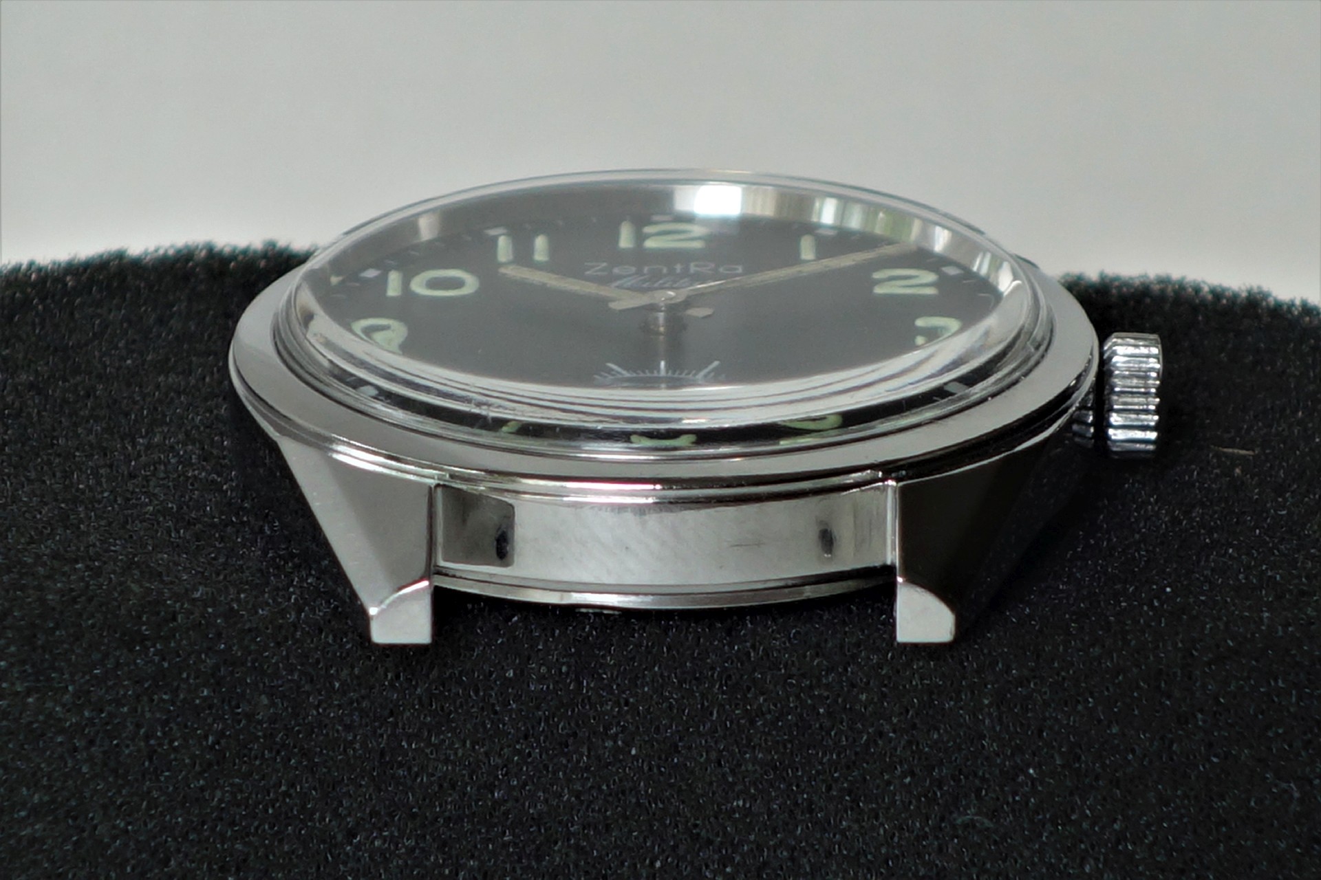 Schwarze Armbanduhr mit silberfarbenem Gehäuse und Leuchtziffern.