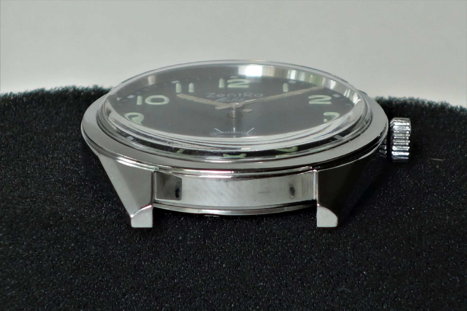 Schwarze Armbanduhr mit silberfarbenem Gehäuse und Leuchtziffern.