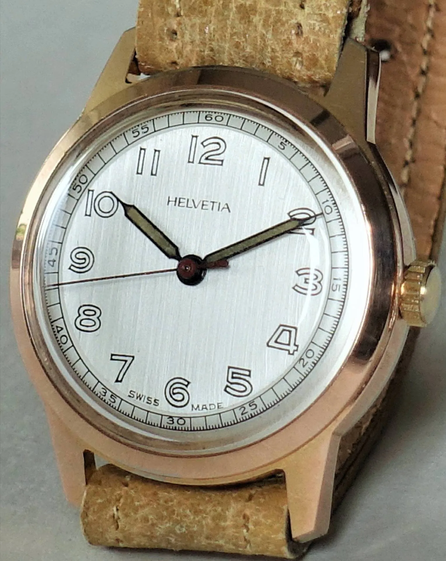 Helvetia Armbanduhr beige Beige Armbanduhr mit silberfarbenem Zifferblatt und braunem Lederarmband.