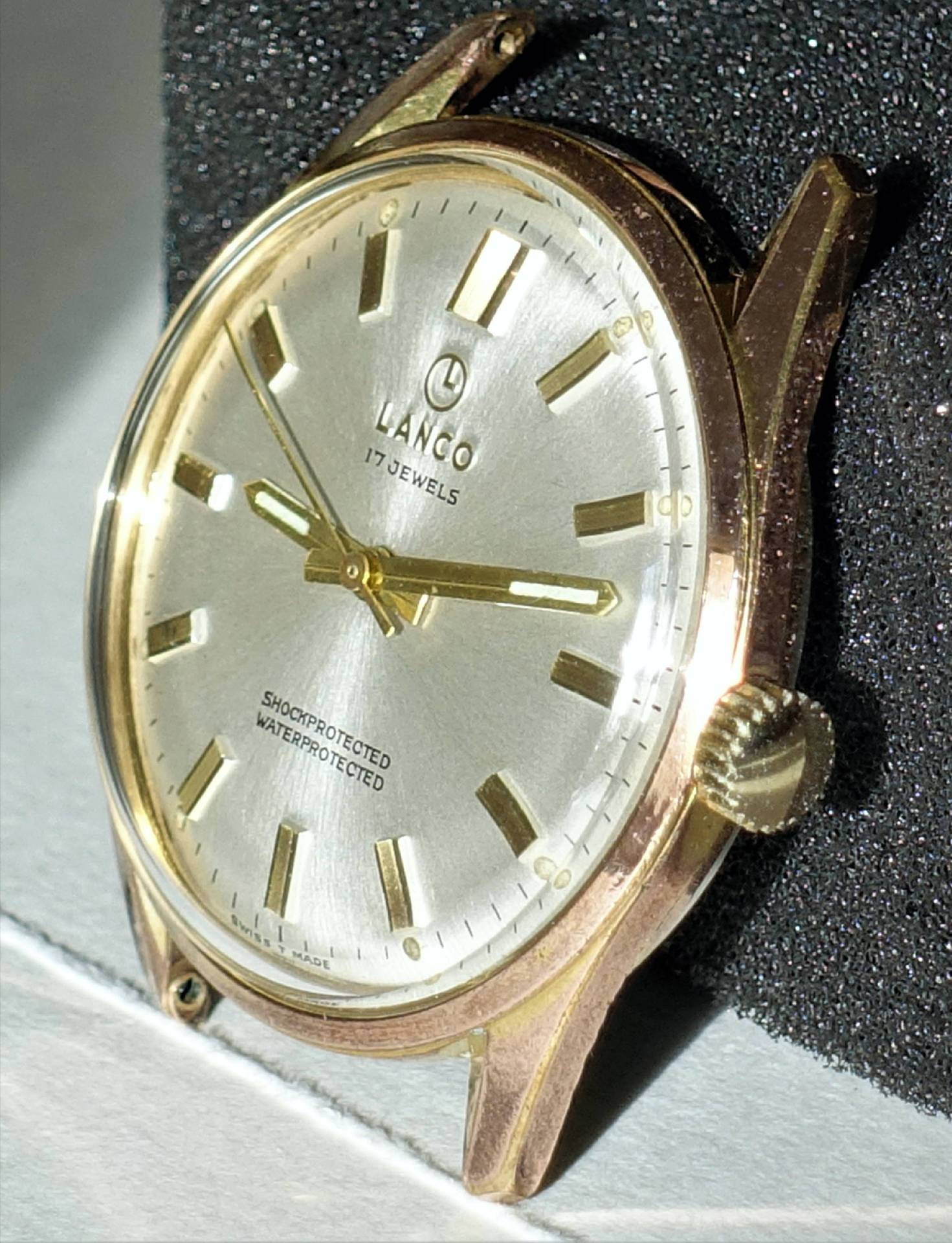 Goldfarbene Armbanduhr mit silbernem Zifferblatt und goldenen Indizes.