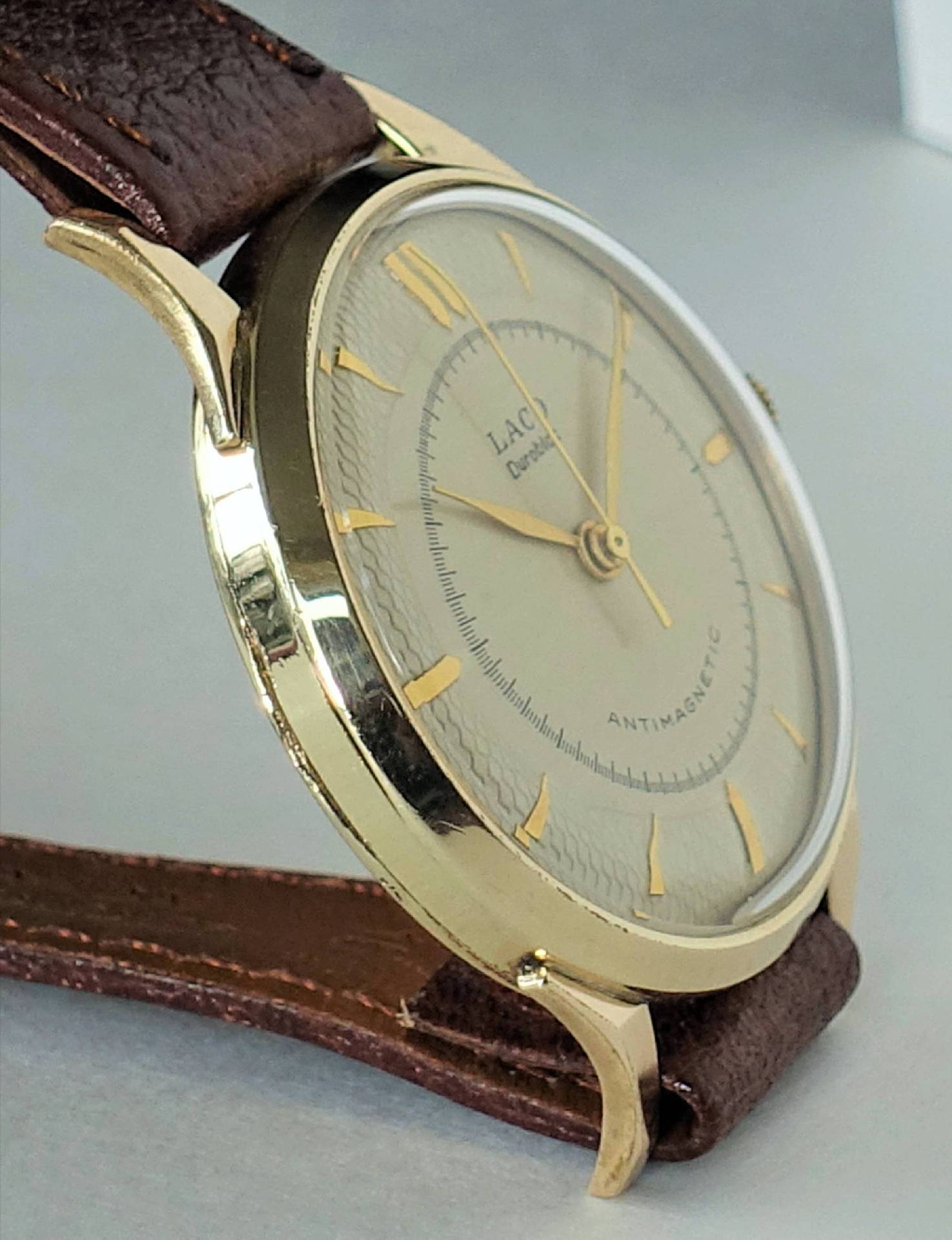 Analoge Armbanduhr mit goldfarbenem Gehäuse und braunem Armband.