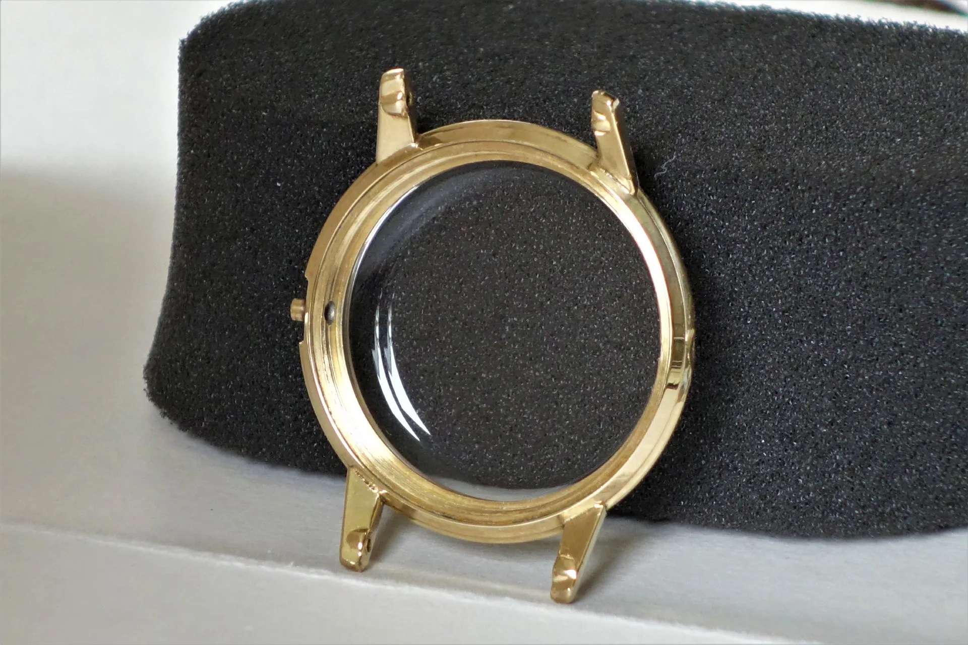 Rundes Uhrengehäuse in goldfarbener Optik mit montiertem Uhrglas.