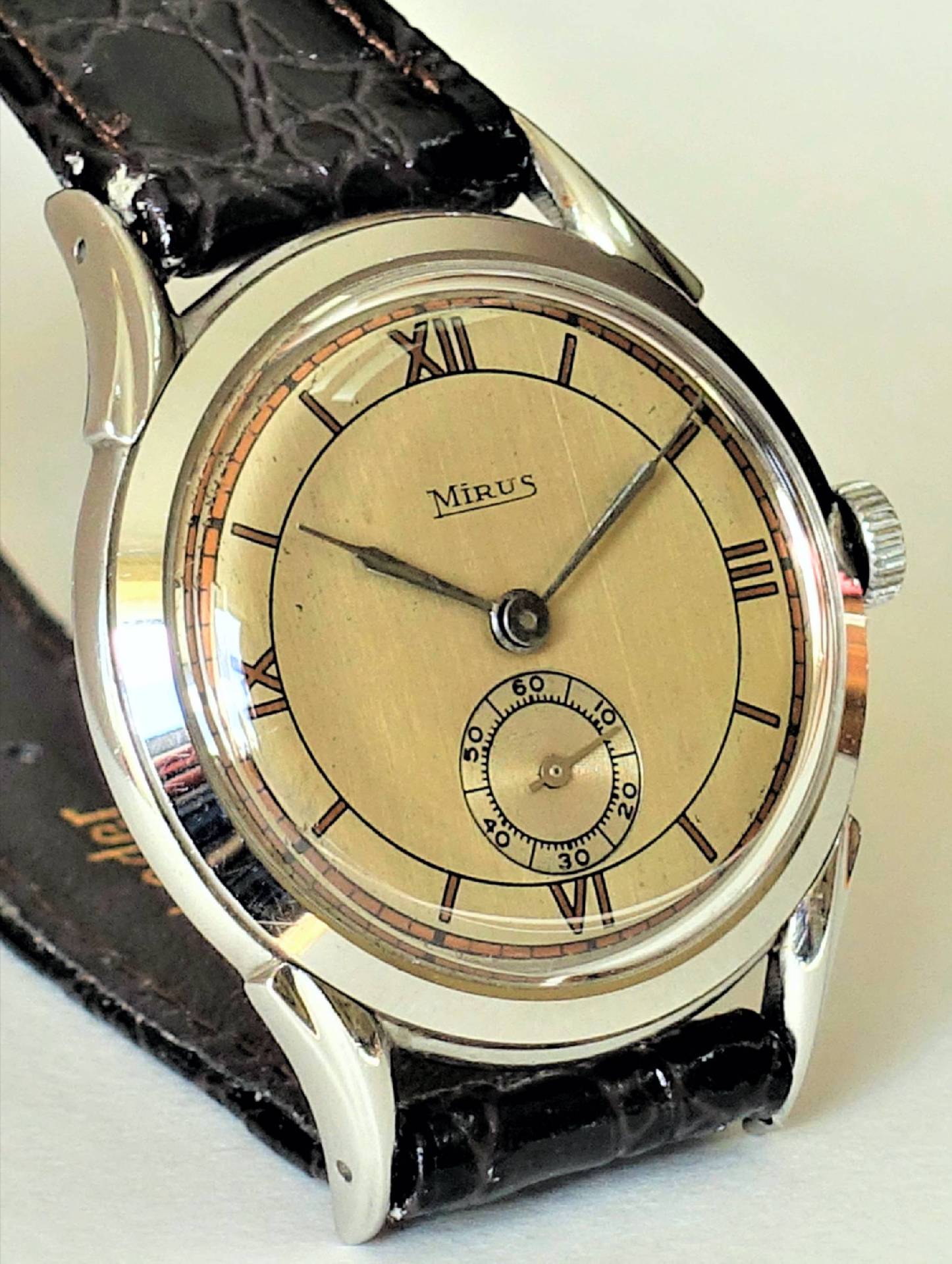 Eine klassische Armbanduhr mit beigem Zifferblatt, schwarzen römischen Zahlen und schwarzem Armband.