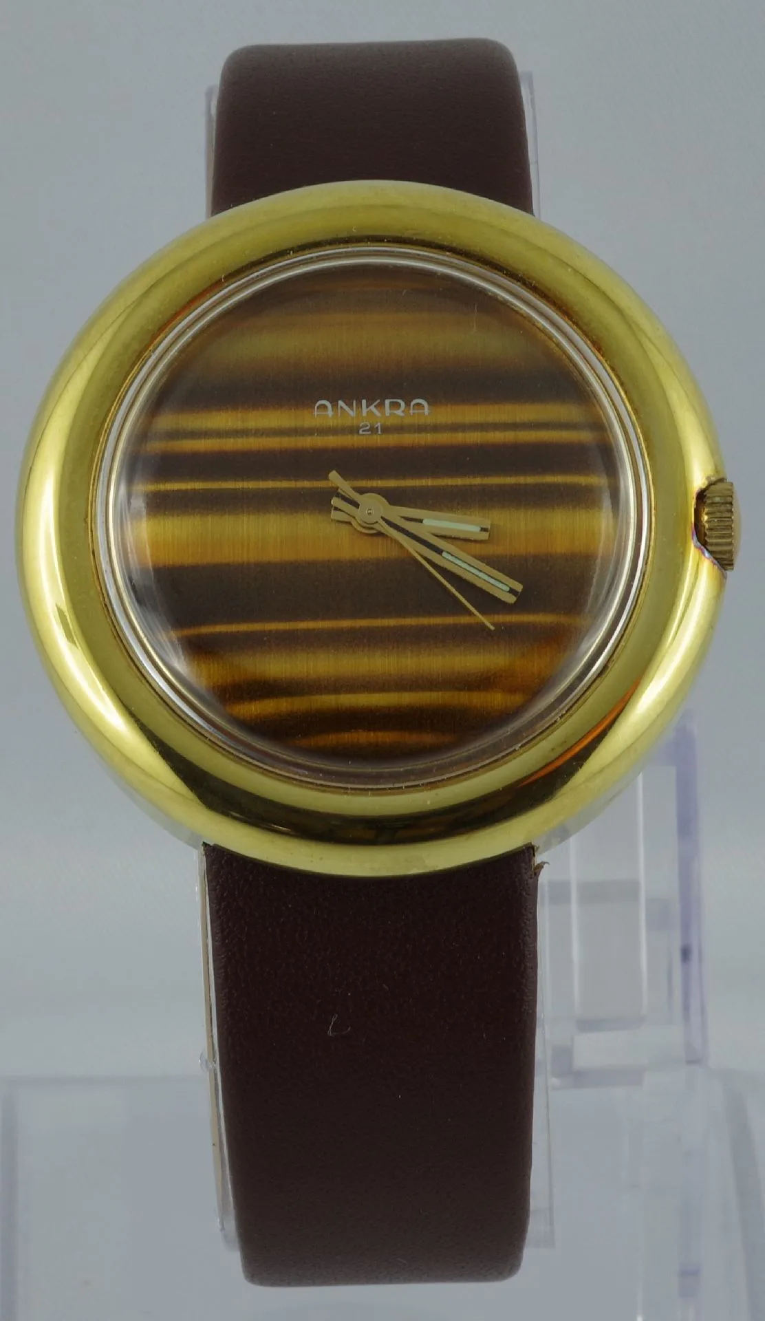 Armbanduhr goldfarben braun Analoge Armbanduhr mit goldfarbenem Gehäuse, braunem Lederarmband und gestreiftem Zifferblatt.