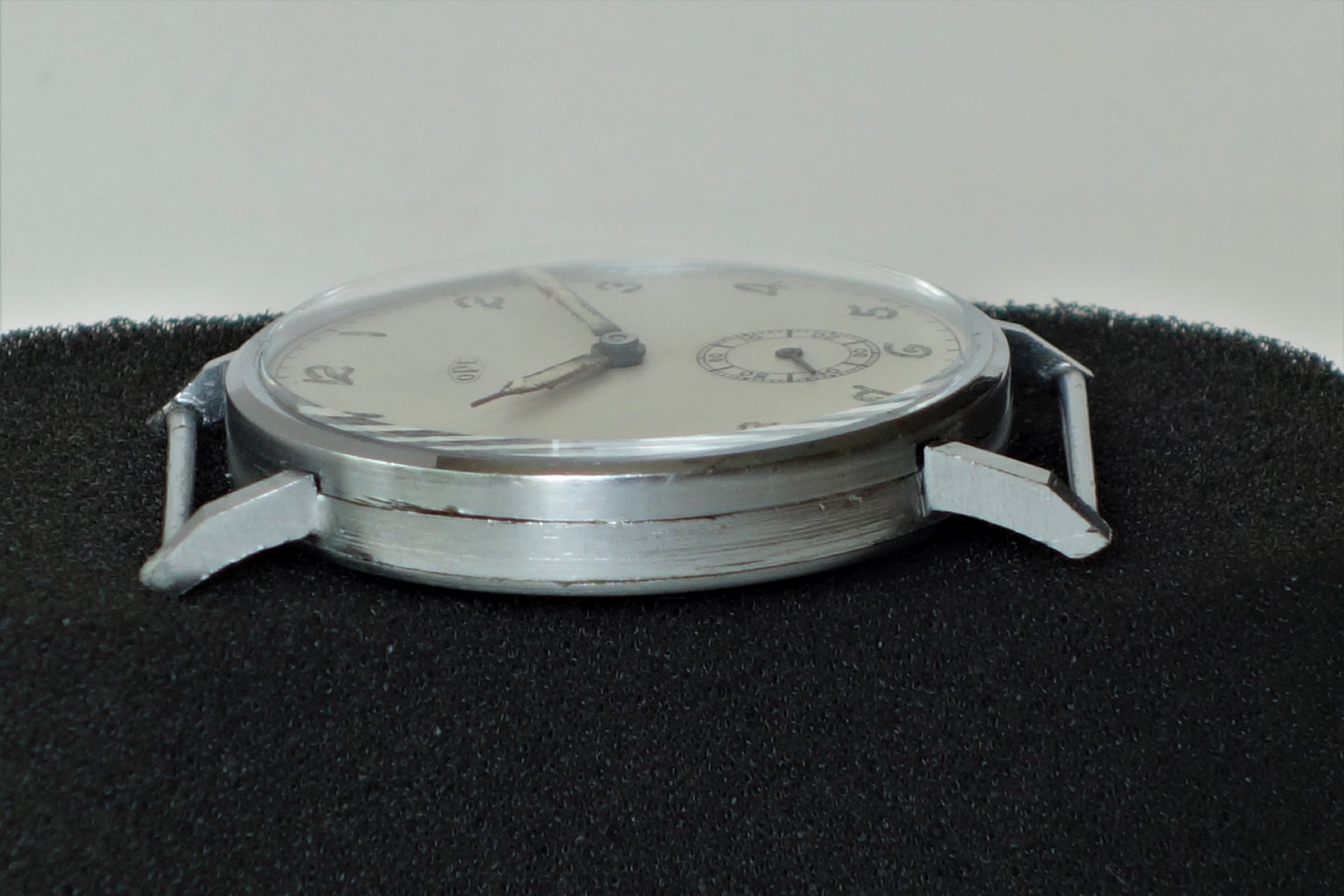 Flache Armbanduhr mit silberfarbenem Gehäuse und hellem Zifferblatt ohne Armband.