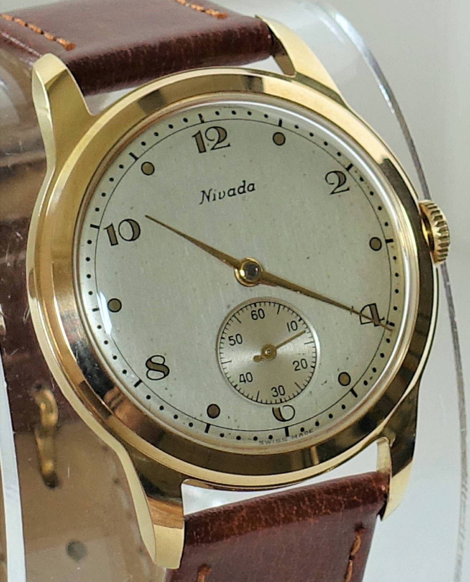 Goldfarbene Armbanduhr mit hellem Zifferblatt und braunem Lederarmband.