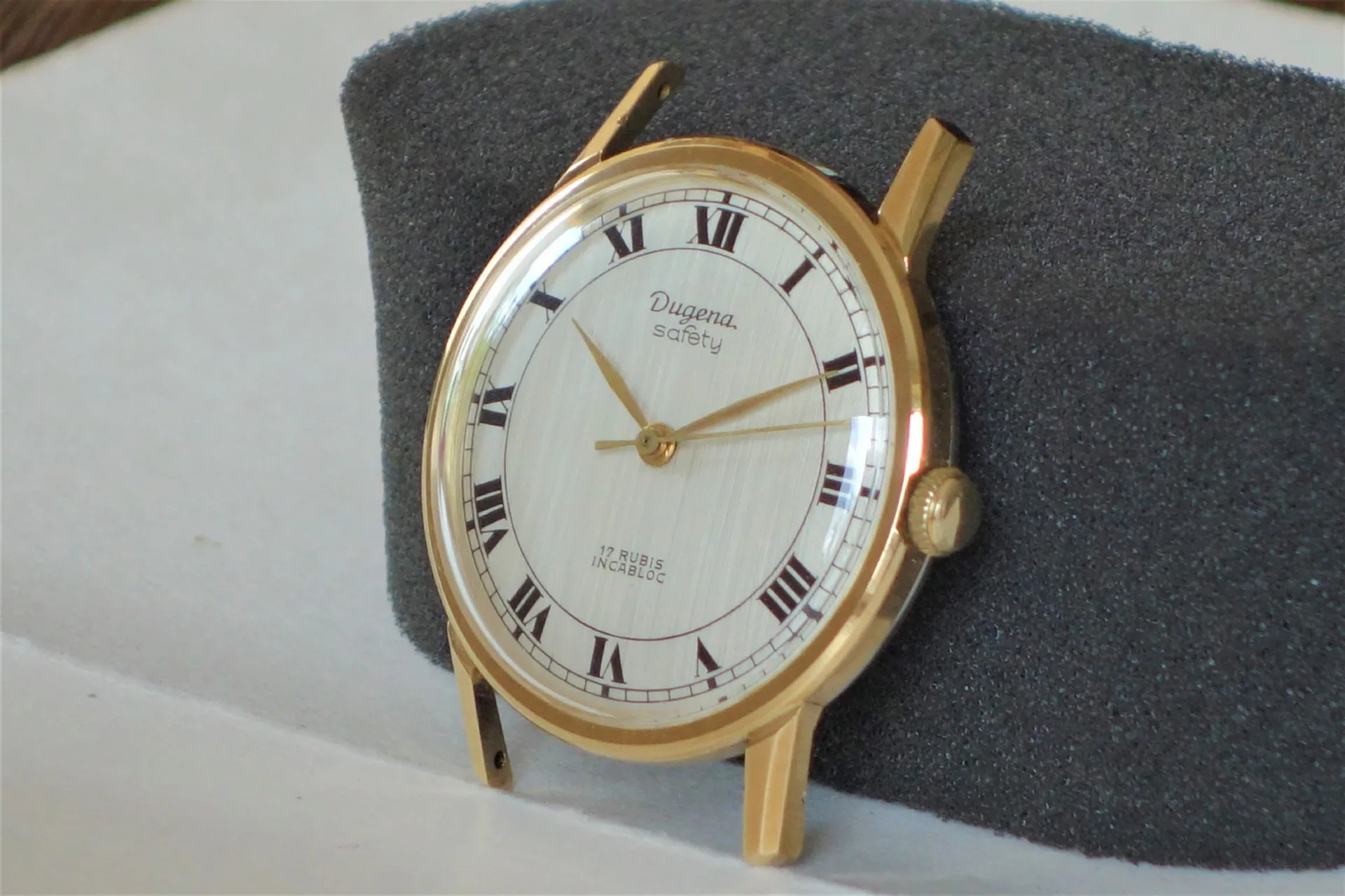 Runde Armbanduhr mit goldfarbenem Gehäuse und weißem Zifferblatt mit römischen Zahlen.