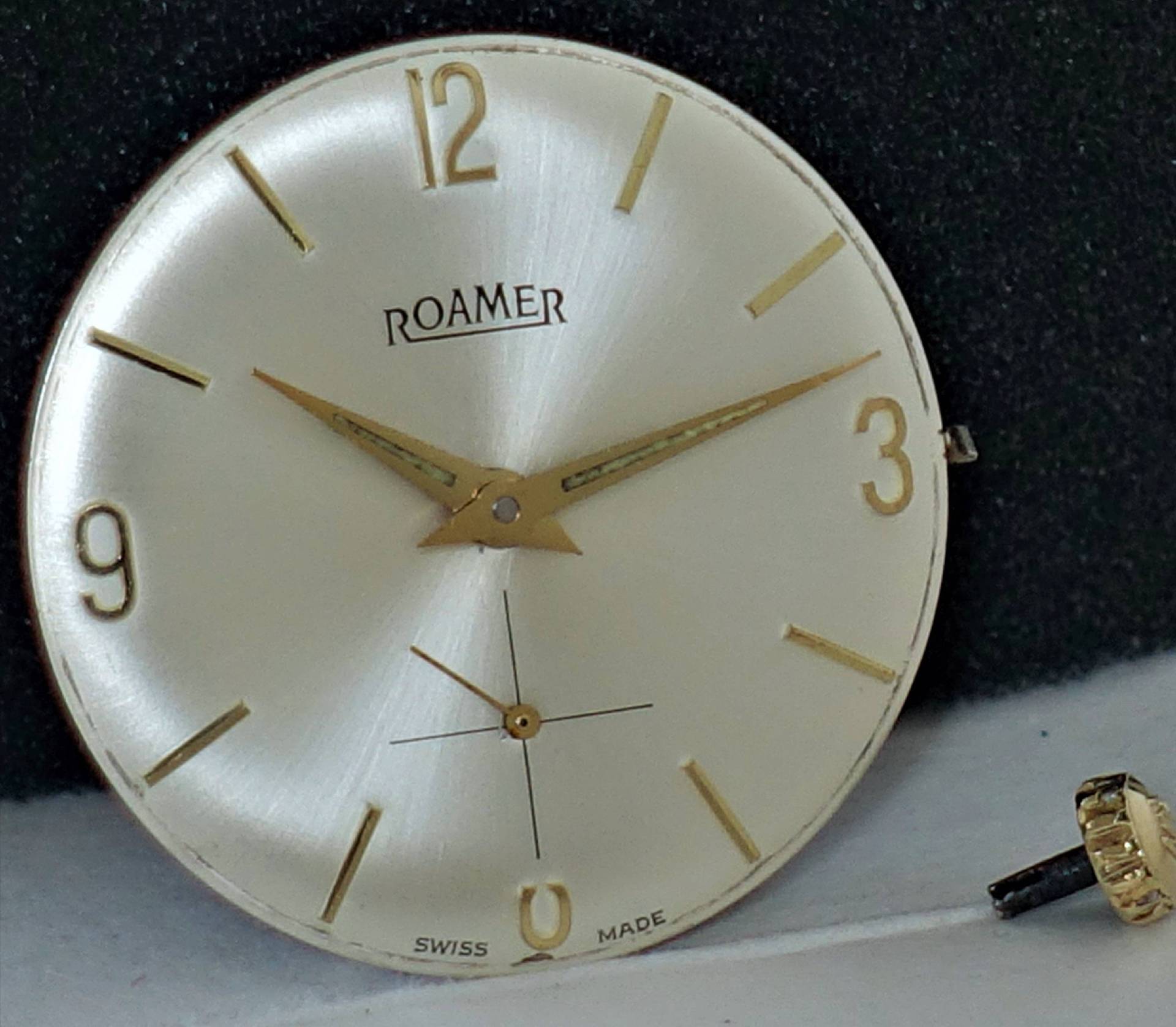 Rundes Zifferblatt einer Roamer Uhr in goldfarbener Optik mit goldfarbenen Zeigern und abgetrennter Krone.