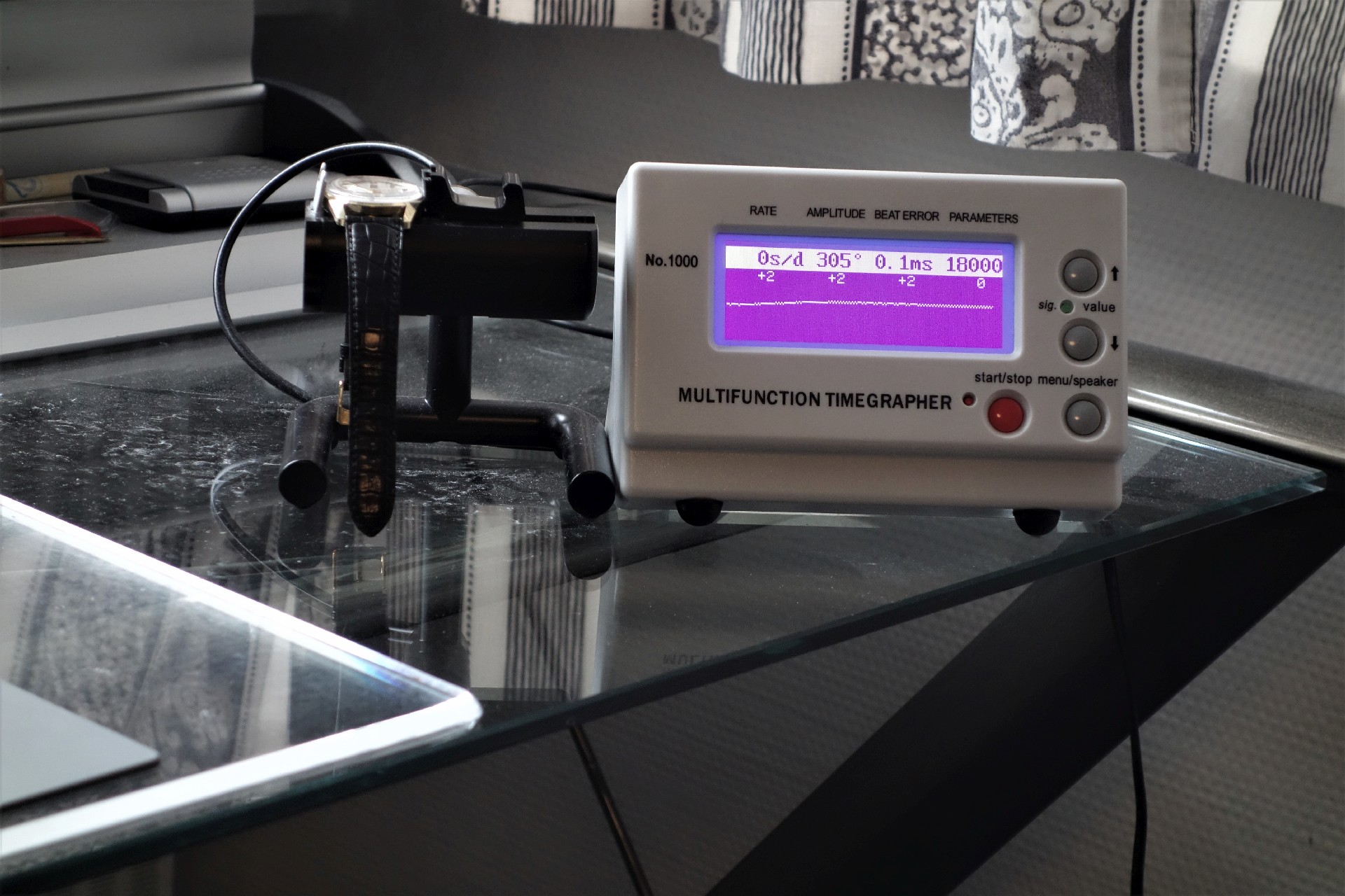 Elektronisches Prüfgerät zur Messung der Gangwerte mechanischer Uhren, mit angeschlossener Armbanduhr.