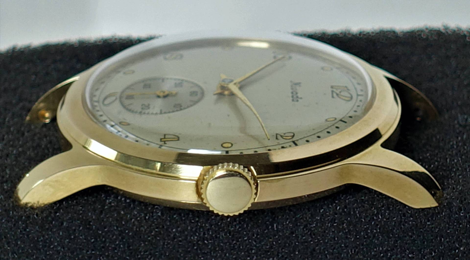 Goldfarbene Armbanduhr mit hellem Zifferblatt und zentraler Krone.