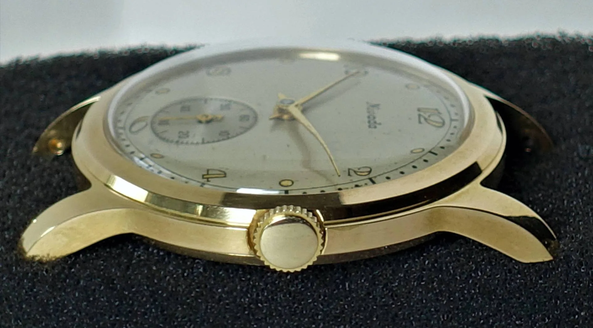 Goldfarbene Armbanduhr mit hellem Zifferblatt und zentraler Krone.