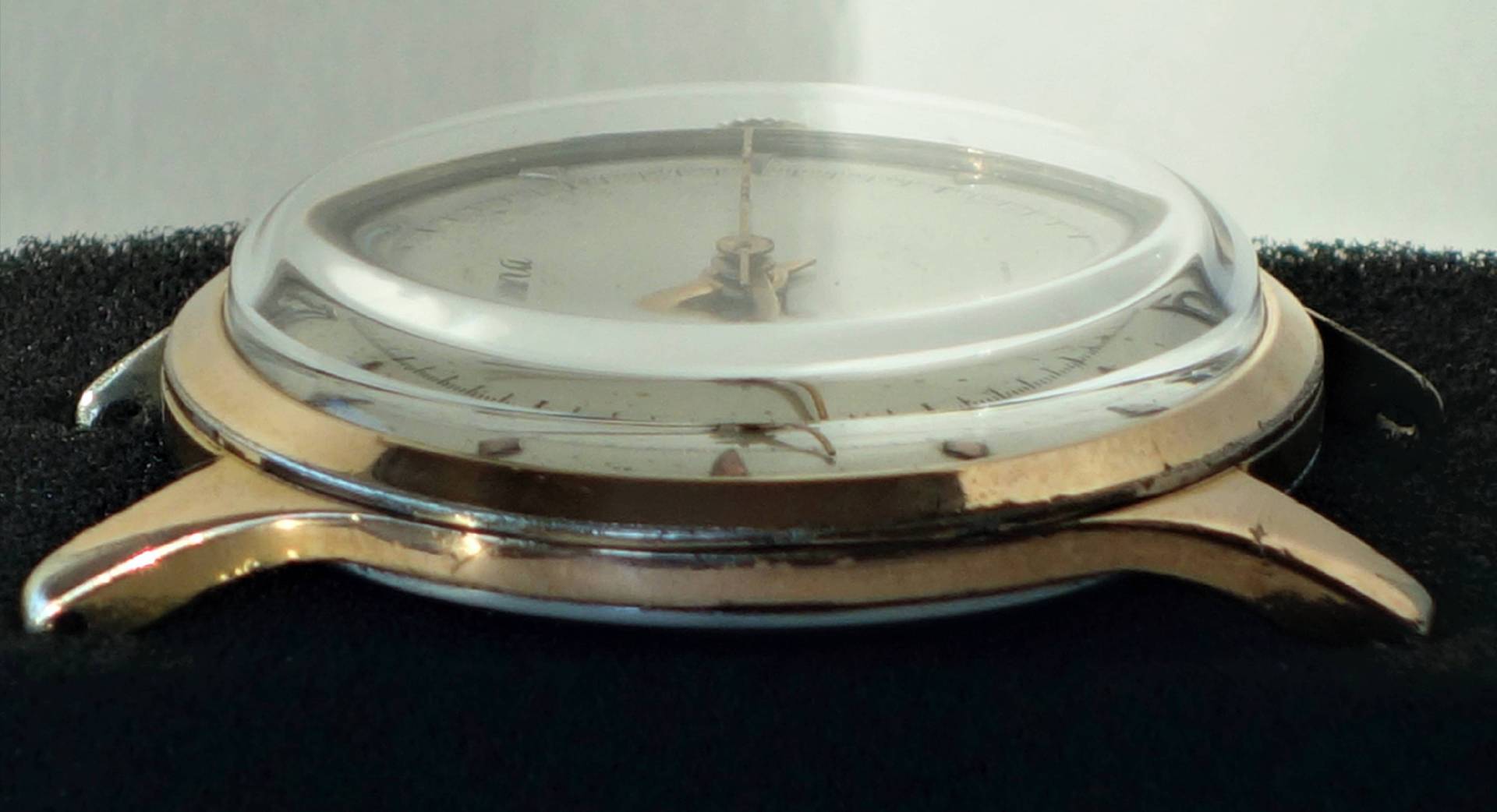 Goldfarbenes Uhrgehäuse mit montiertem Uhrglas und Zifferblatt ohne Armband.