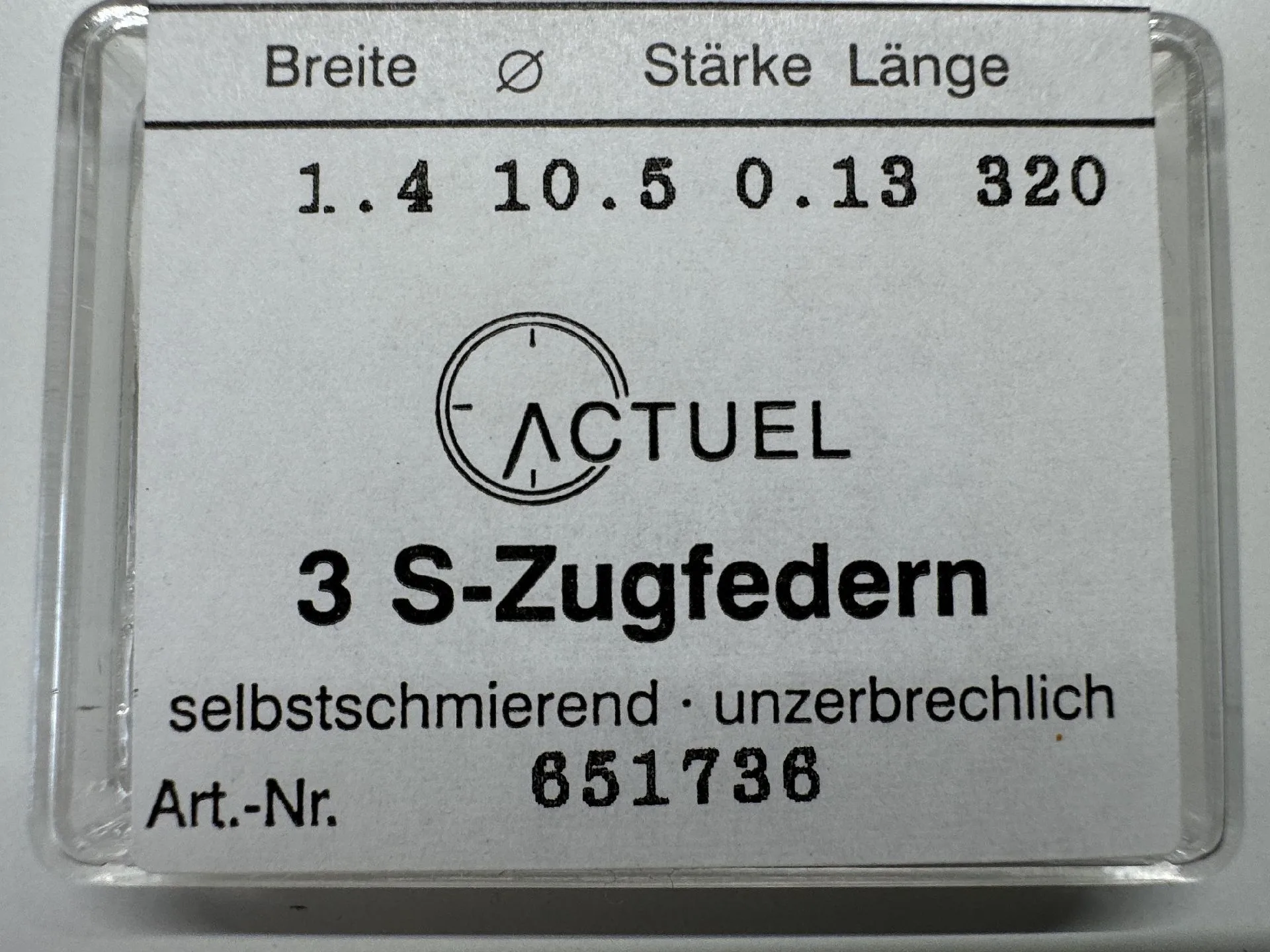 Zugfeder Set Uhrwerk Drei silberfarbene Zugfedern für Uhrwerke in transparenter Verpackung.