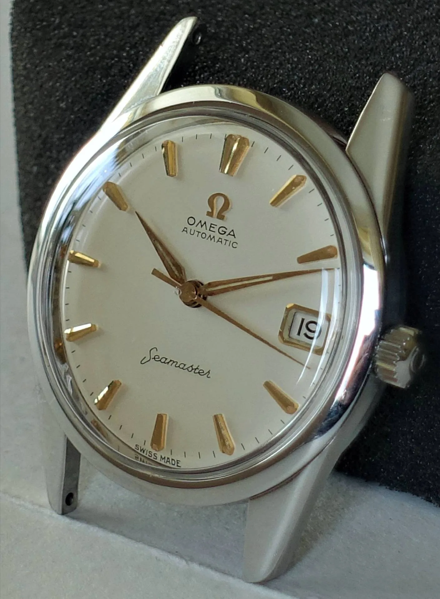 Silberne Armbanduhr mit weißem Zifferblatt und goldfarbenen Indizes und Zeigern.