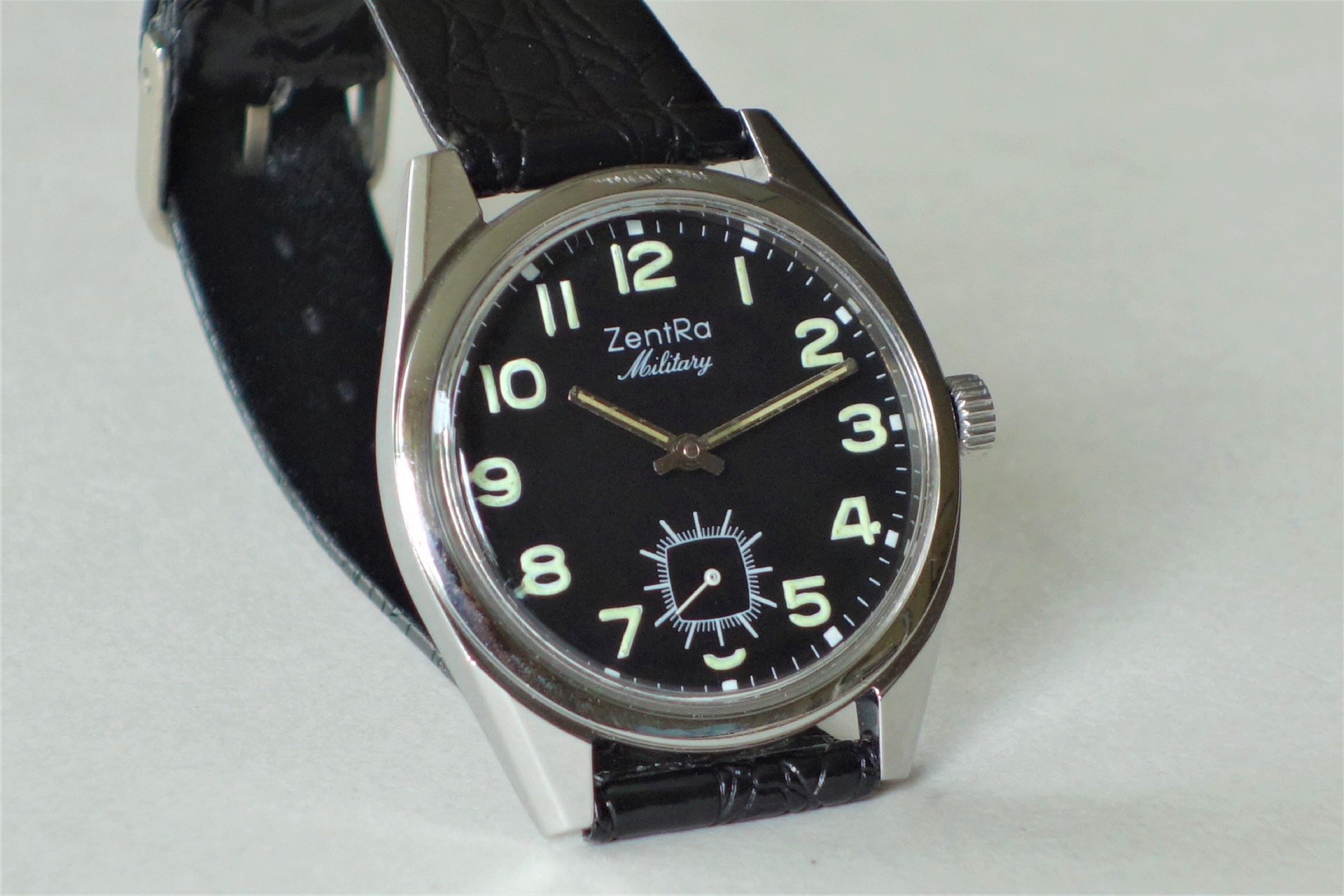 Schwarze Armbanduhr mit Leuchtziffern und schwarzem Armband.