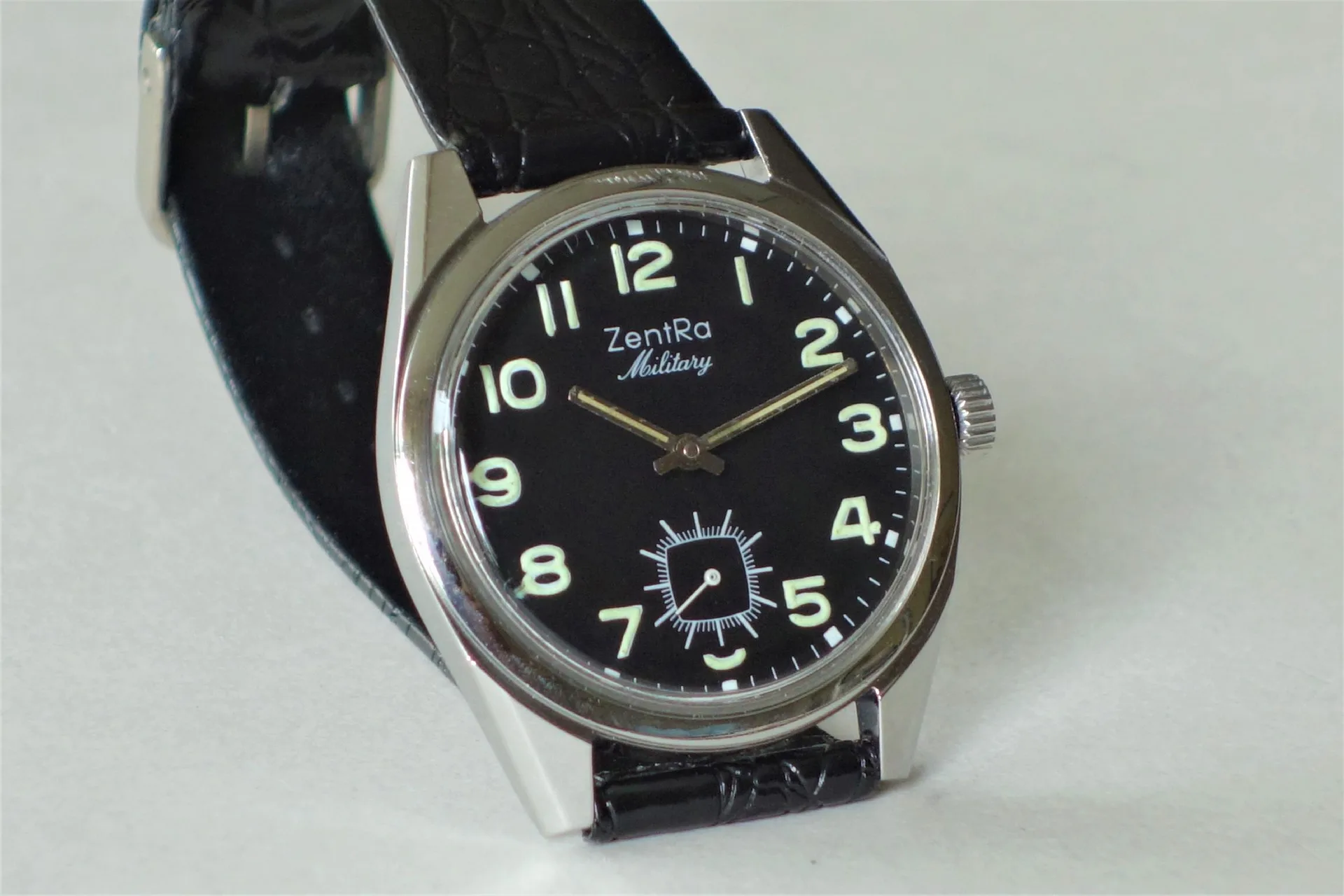 Schwarze Armbanduhr mit Leuchtziffern und schwarzem Armband.