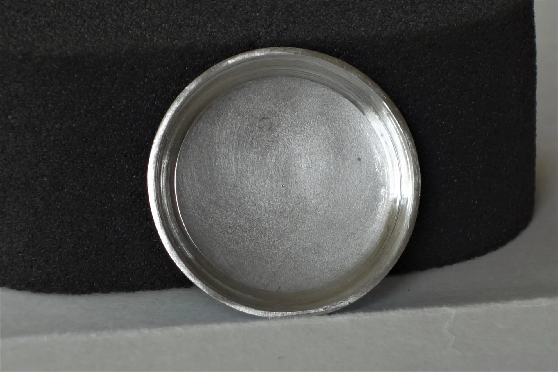 Runder silberfarbener Uhrenboden aus Metall.