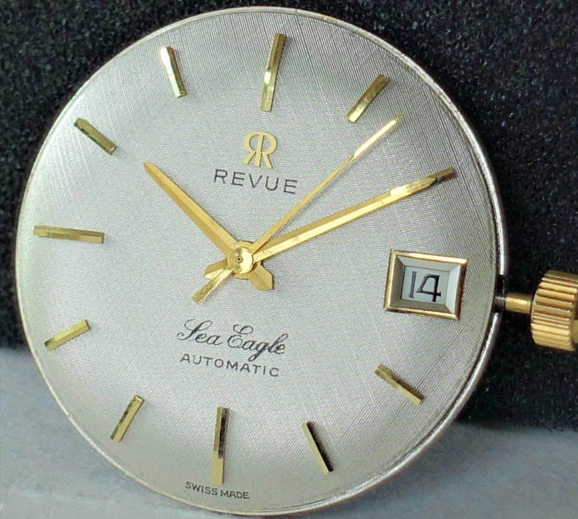 Zifferblatt Revue Sea Eagle Silberfarbenes Zifferblatt mit goldfarbenen Zeigern und Indizes, Datumsanzeige bei drei Uhr.
