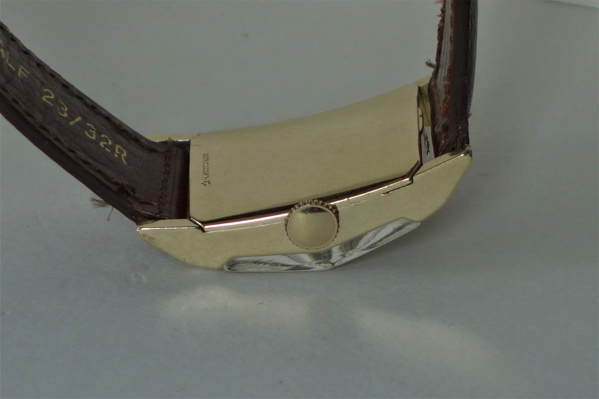 Goldfarbenes Uhrgehäuse mit braunem Armband und seitlicher Krone.