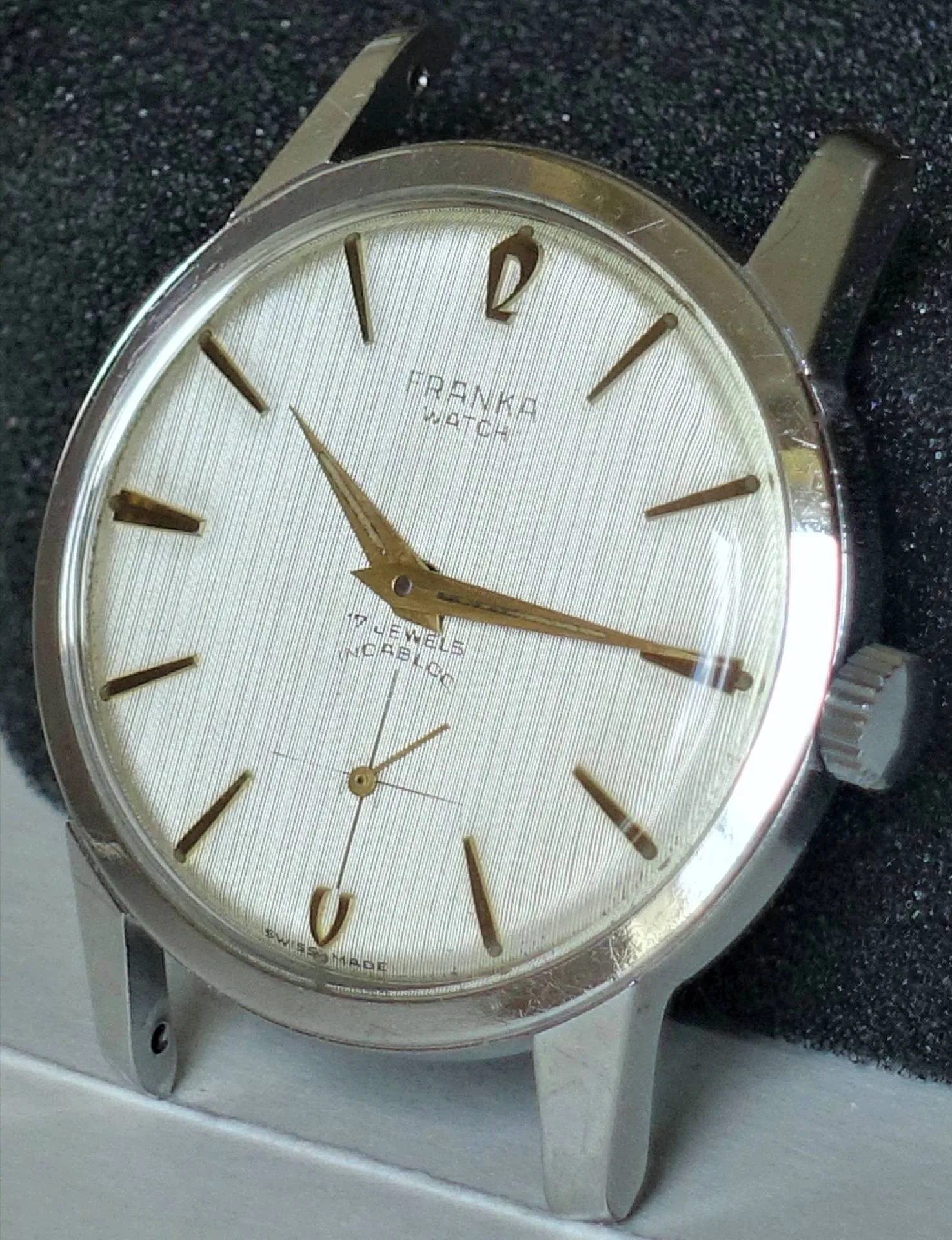 Silberfarbene Armbanduhr mit hellem Zifferblatt und goldfarbenen Indizes und Zeigern.