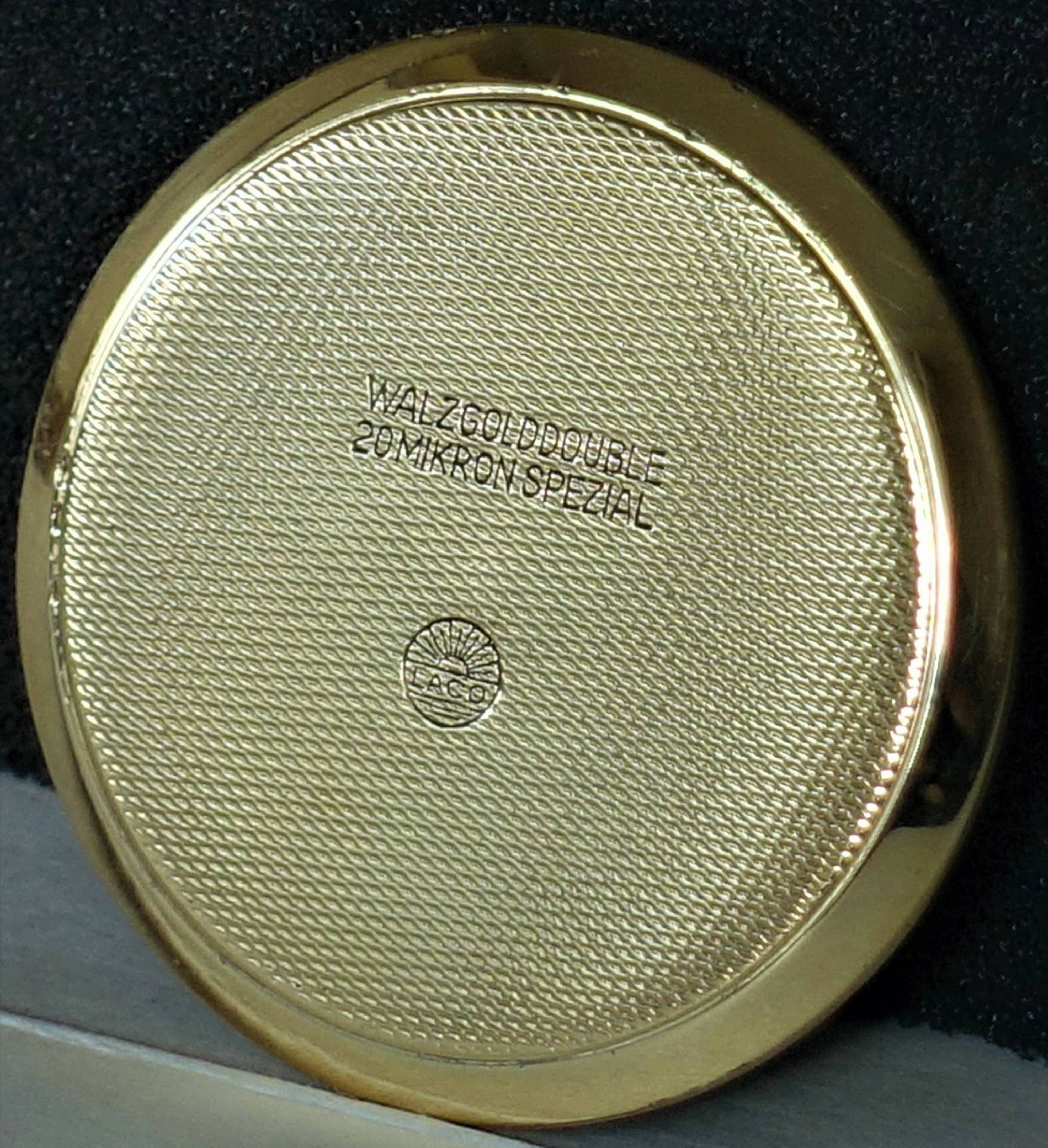 Runder Uhrenboden in goldfarbener Optik mit feiner Struktur und Gravur.