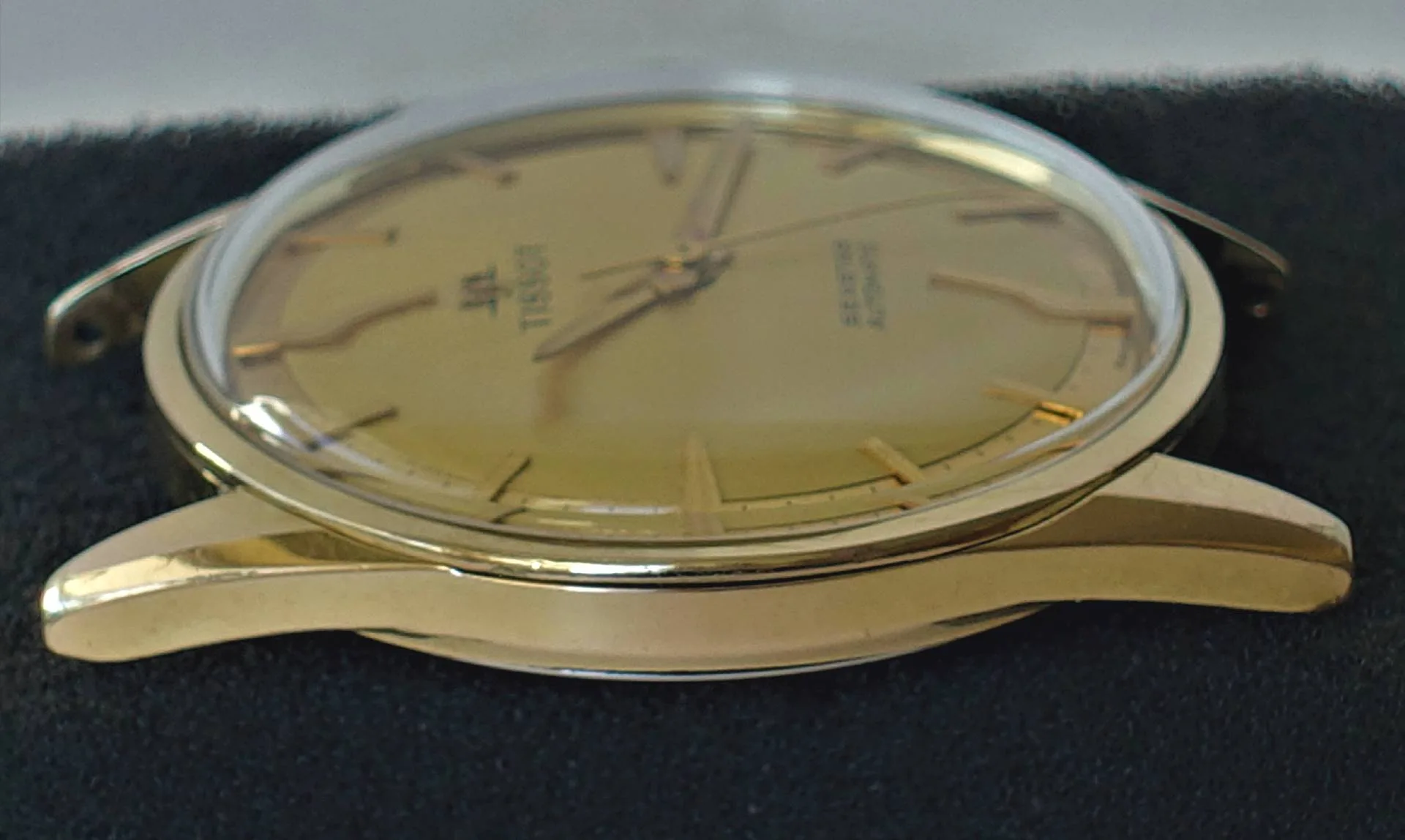 Goldfarbene Armbanduhr mit rundem Gehäuse und goldfarbenem Zifferblatt.