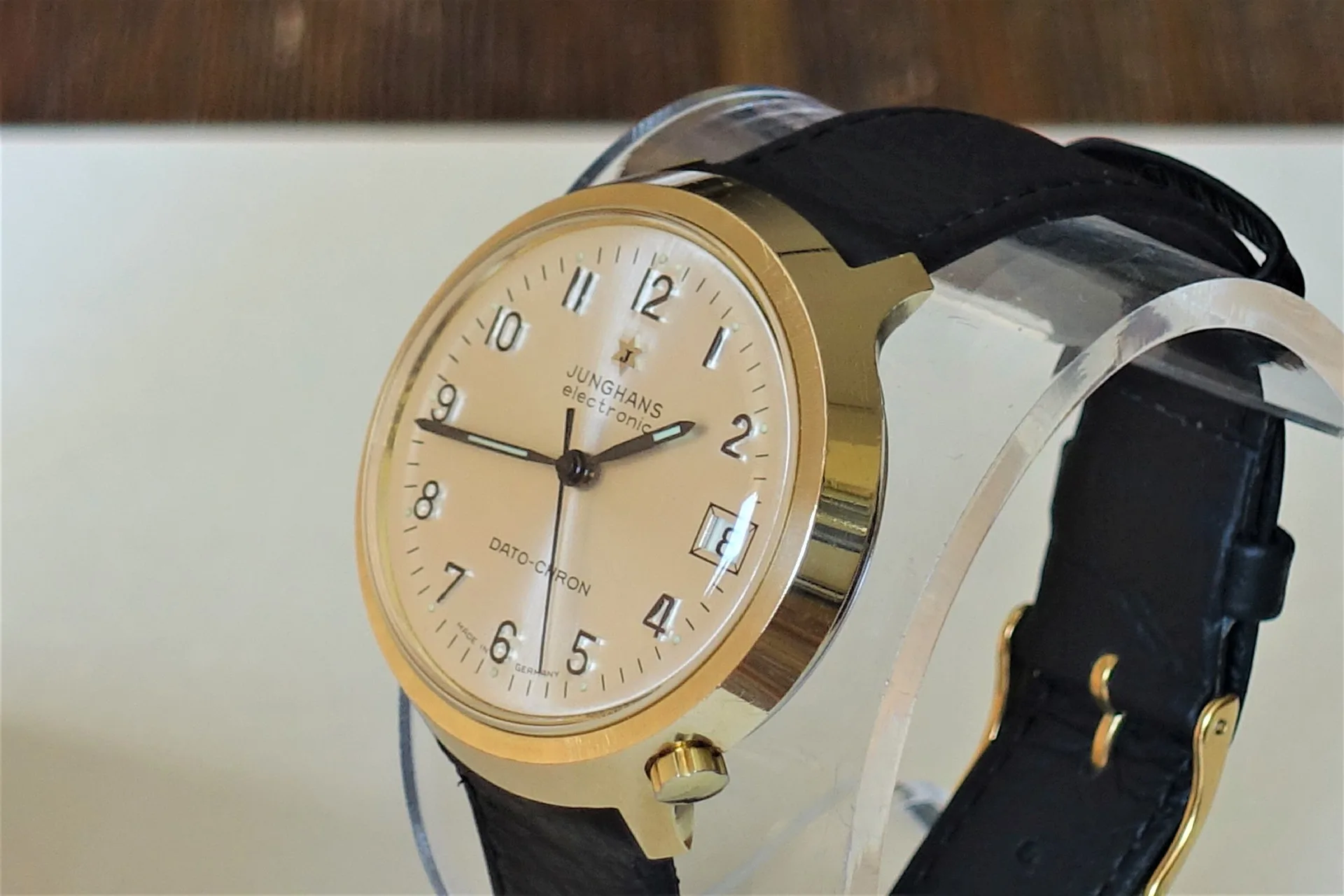 Goldfarbene Armbanduhr mit hellem Zifferblatt und schwarzem Armband.