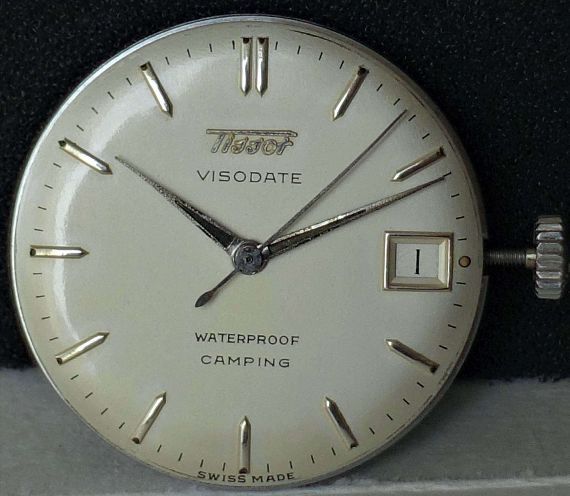 Silberfarbenes Uhrwerk mit weißem Zifferblatt, Datumsanzeige und silbernen Zeigern.