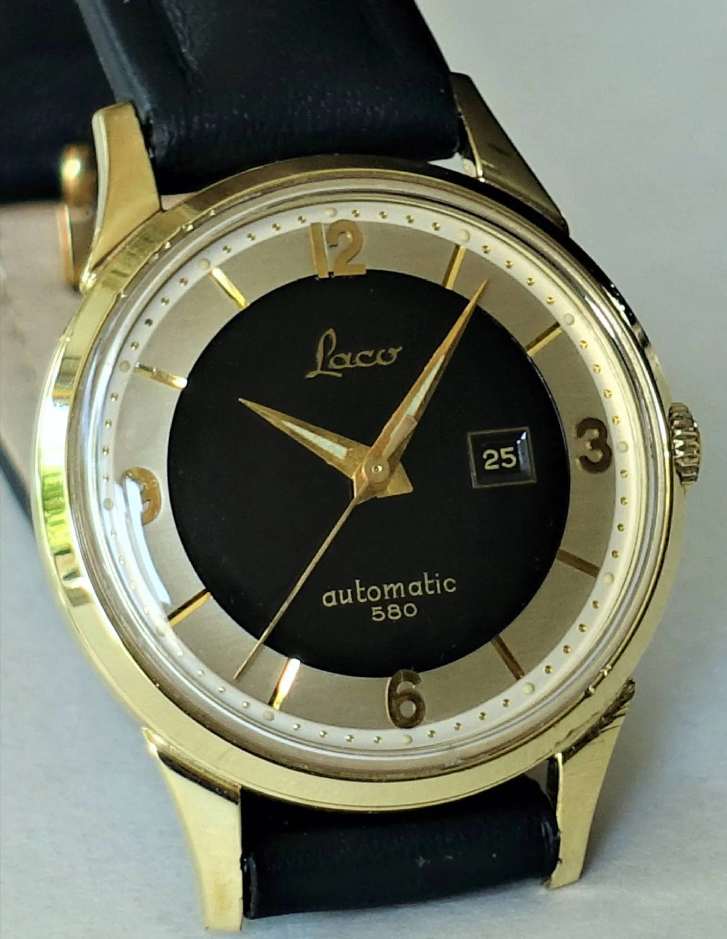 Laco Armbanduhr goldfarben Goldfarbene Armbanduhr mit schwarzem Zifferblatt, Datumsanzeige und schwarzem Armband.