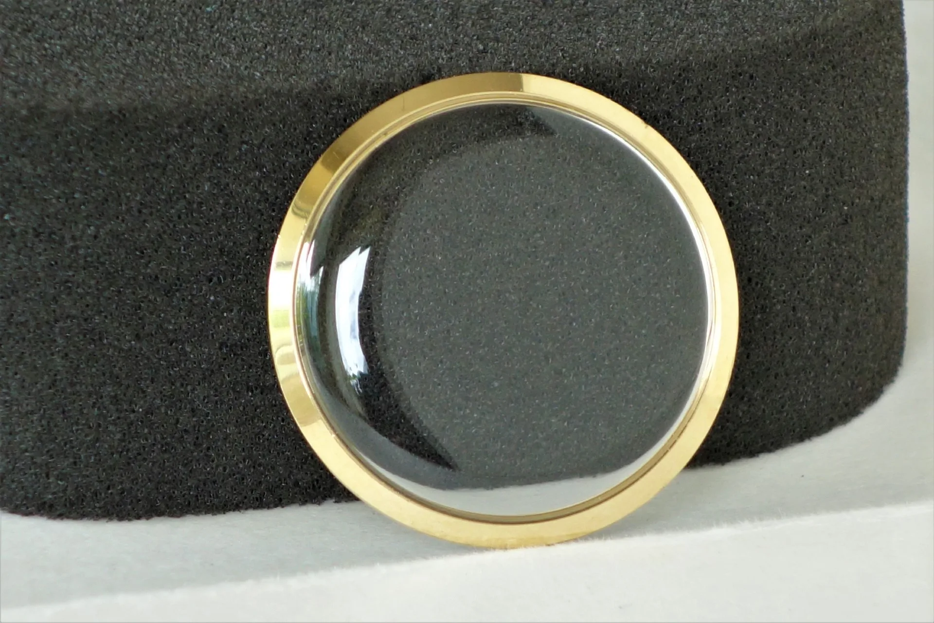 Gewölbtes transparentes Uhrglas mit goldfarbenem Rand.