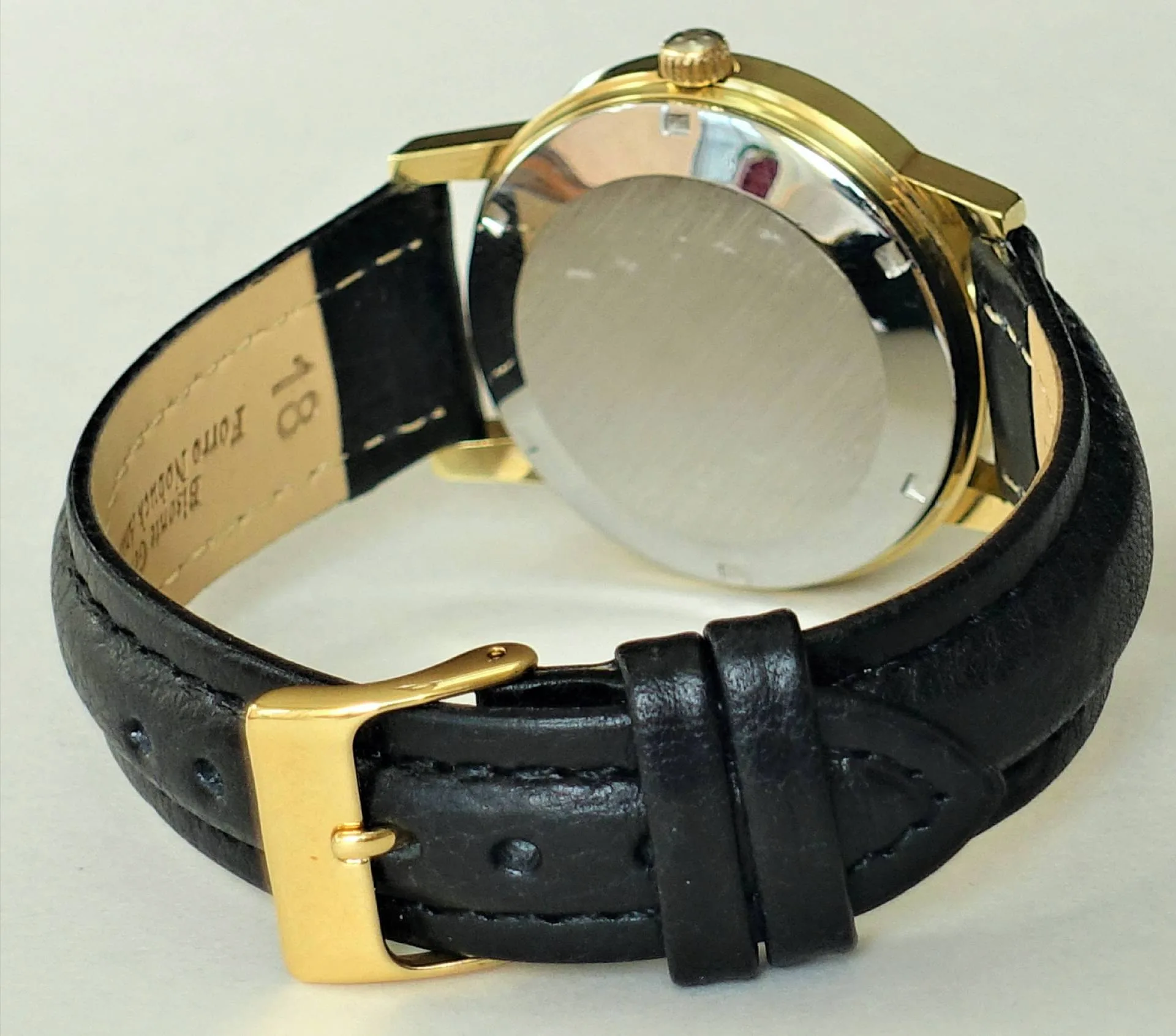 Armbanduhr schwarz goldfarben Schwarze Armbanduhr mit goldfarbenem Gehäuse und Dornschließe, Rückseite sichtbar.