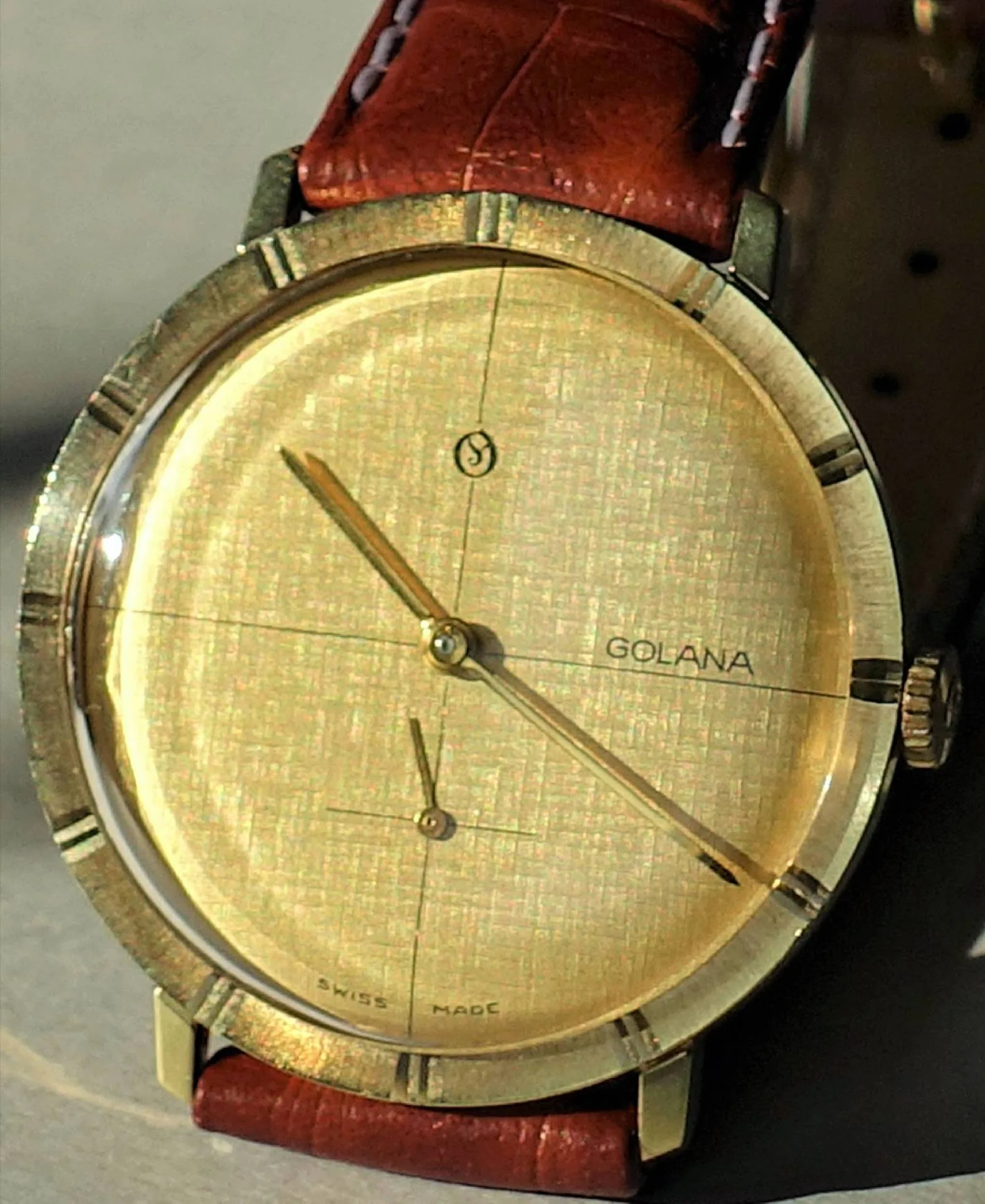 Goldfarbene Armbanduhr mit braunem Armband und schlichtem Zifferblatt.