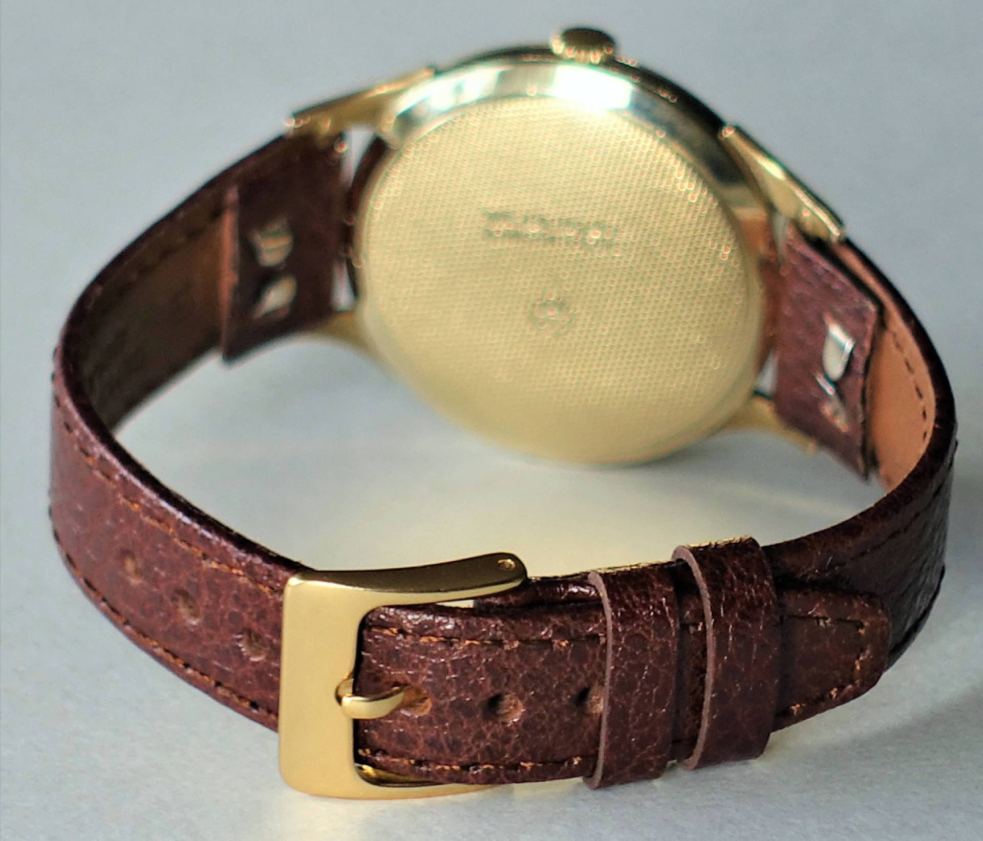 Armbanduhr mit braunem Armband und goldfarbenem Gehäuse.