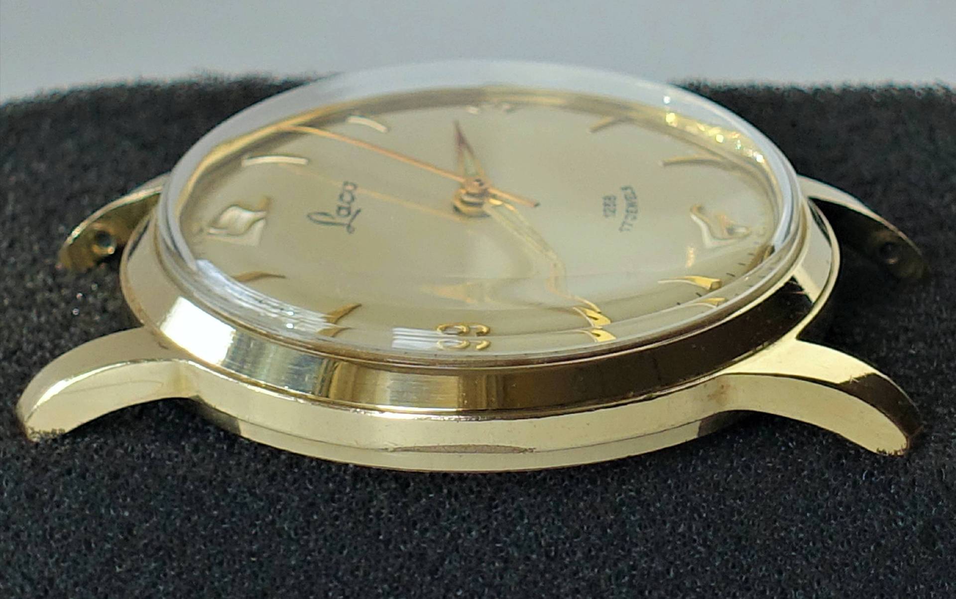 Goldfarbene Armbanduhr mit hellem Zifferblatt und goldenen Zeigern.