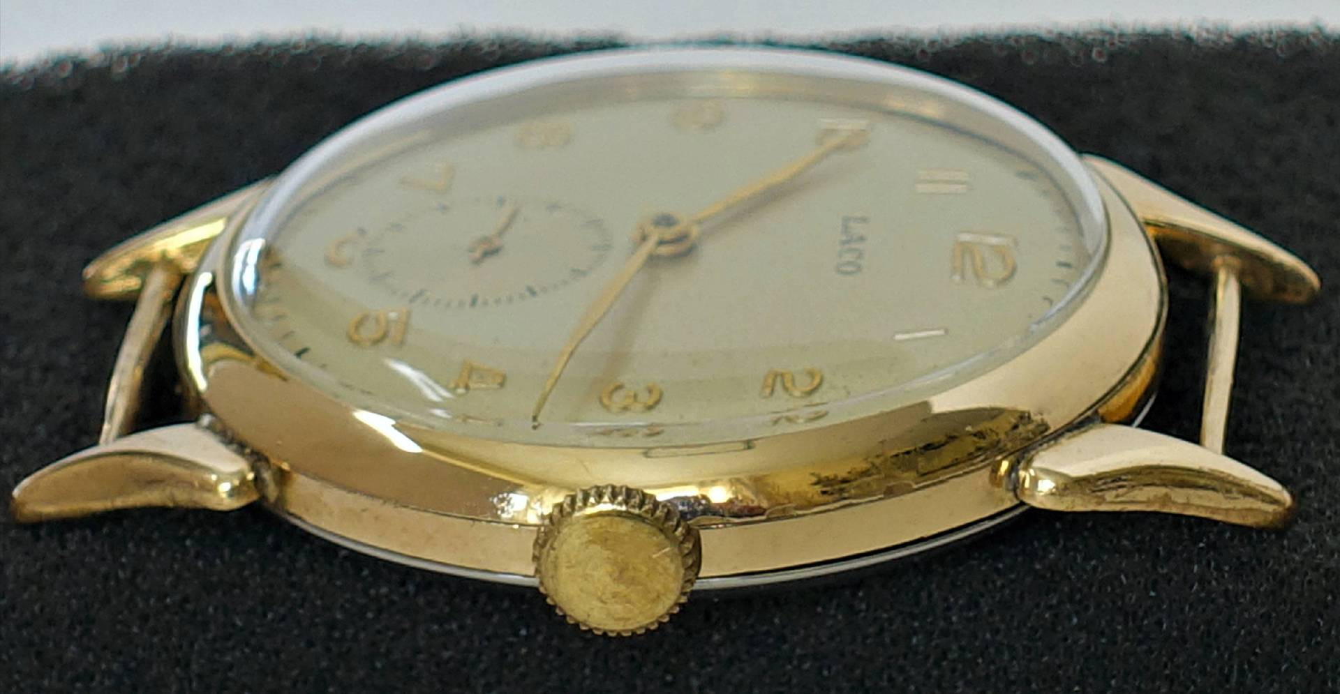 Goldfarbene Armbanduhr mit hellem Zifferblatt und goldenen Zeigern.