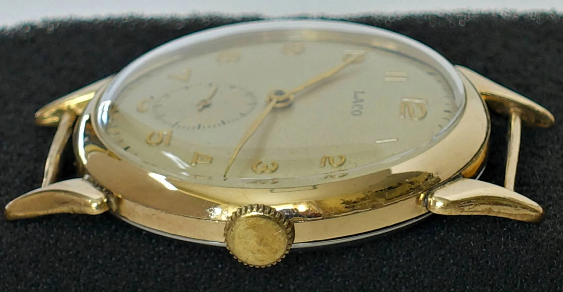 Goldfarbene Armbanduhr mit hellem Zifferblatt und goldenen Zeigern.