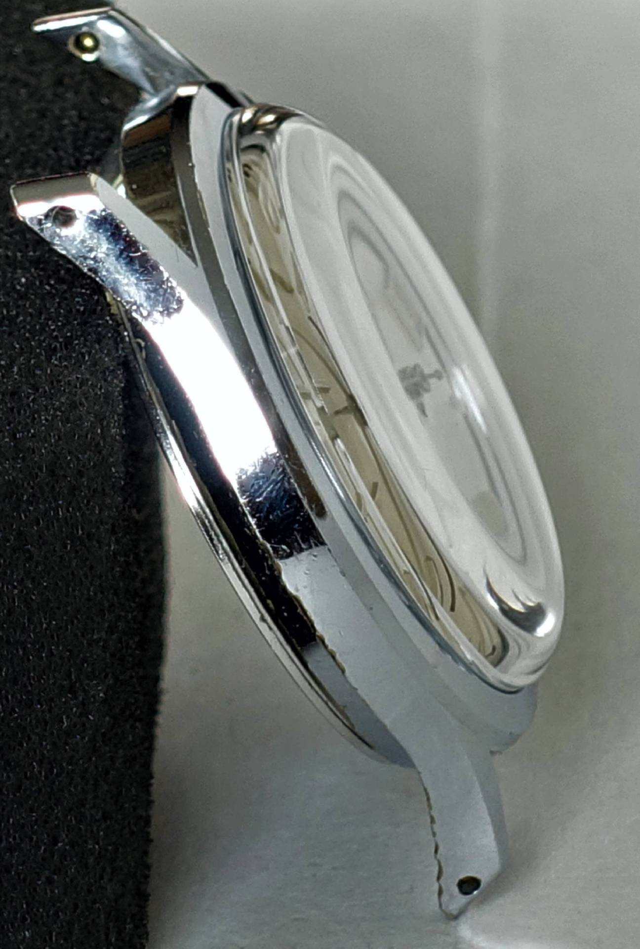 Rundes silberfarbenes Uhrgehäuse mit montiertem Uhrglas, seitliche Ansicht.