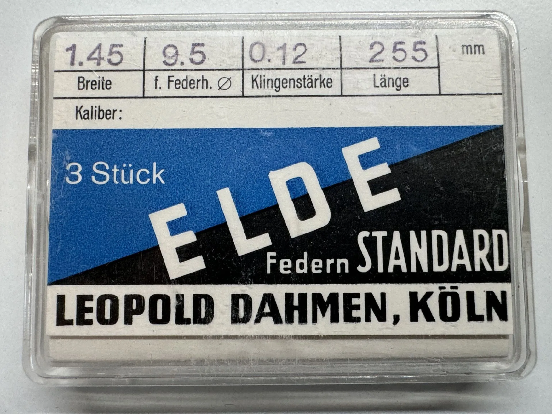 Uhrwerk-Feder Standard Set Set mit drei Uhrwerk-Federn in transparenter Kunststoffbox, beschriftet mit technischen Angaben.