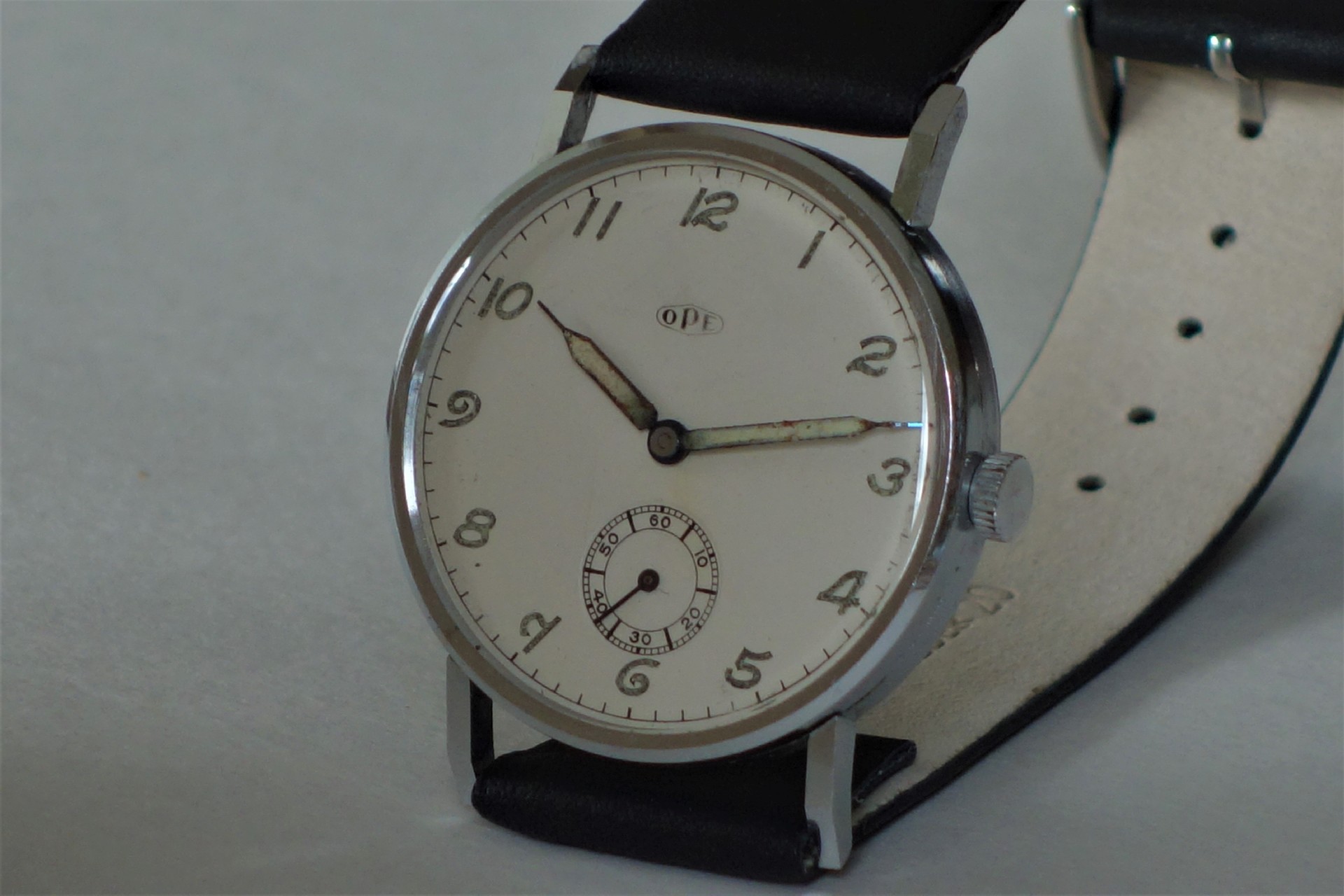 Analoge Armbanduhr mit silberfarbenem Gehäuse, weißem Zifferblatt und schwarzem Armband.