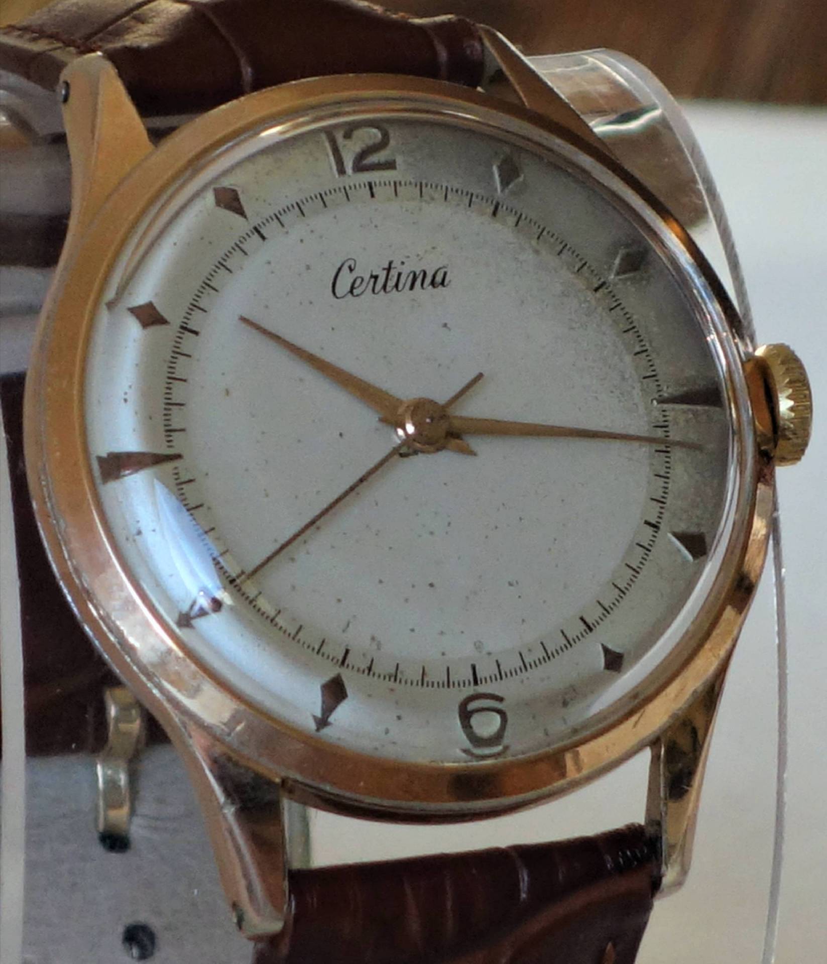 Goldfarbene Certina Armbanduhr mit weißem Zifferblatt und braunem Armband.