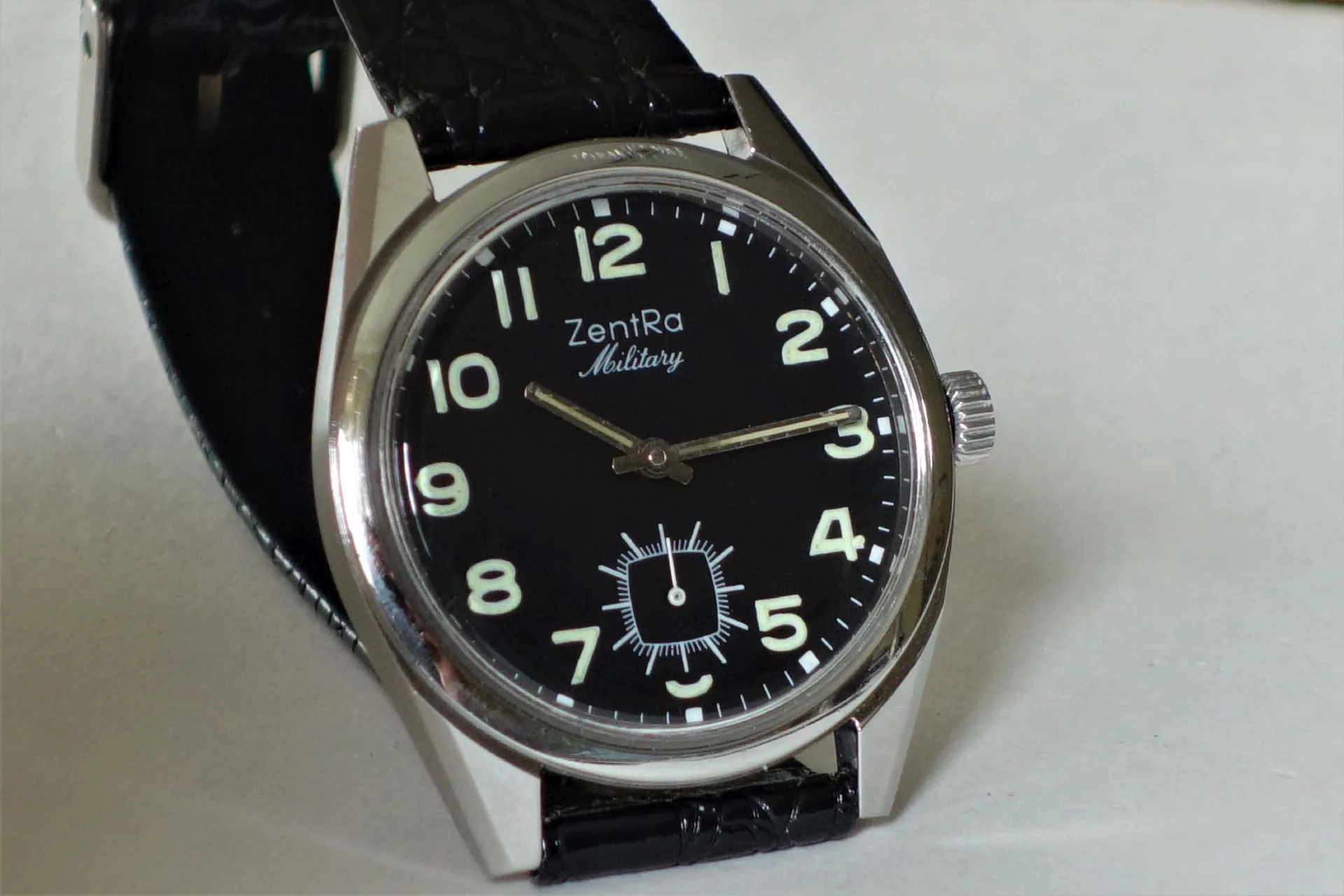 Schwarze Armbanduhr mit hellem Zifferblatt und schwarzem Armband.
