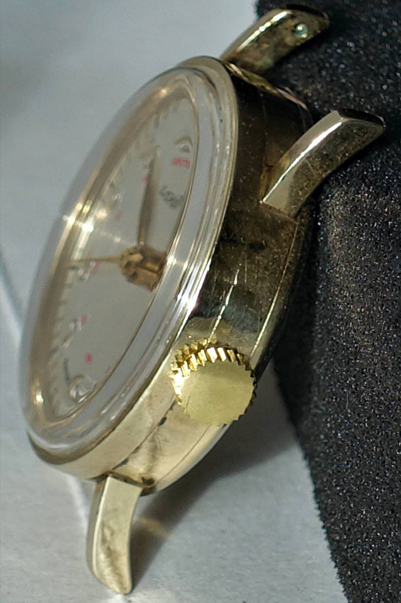 Detailaufnahme einer goldenen Armbanduhr, die von der Seite betrachtet wird. Sie zeigt ein klassisches Design.