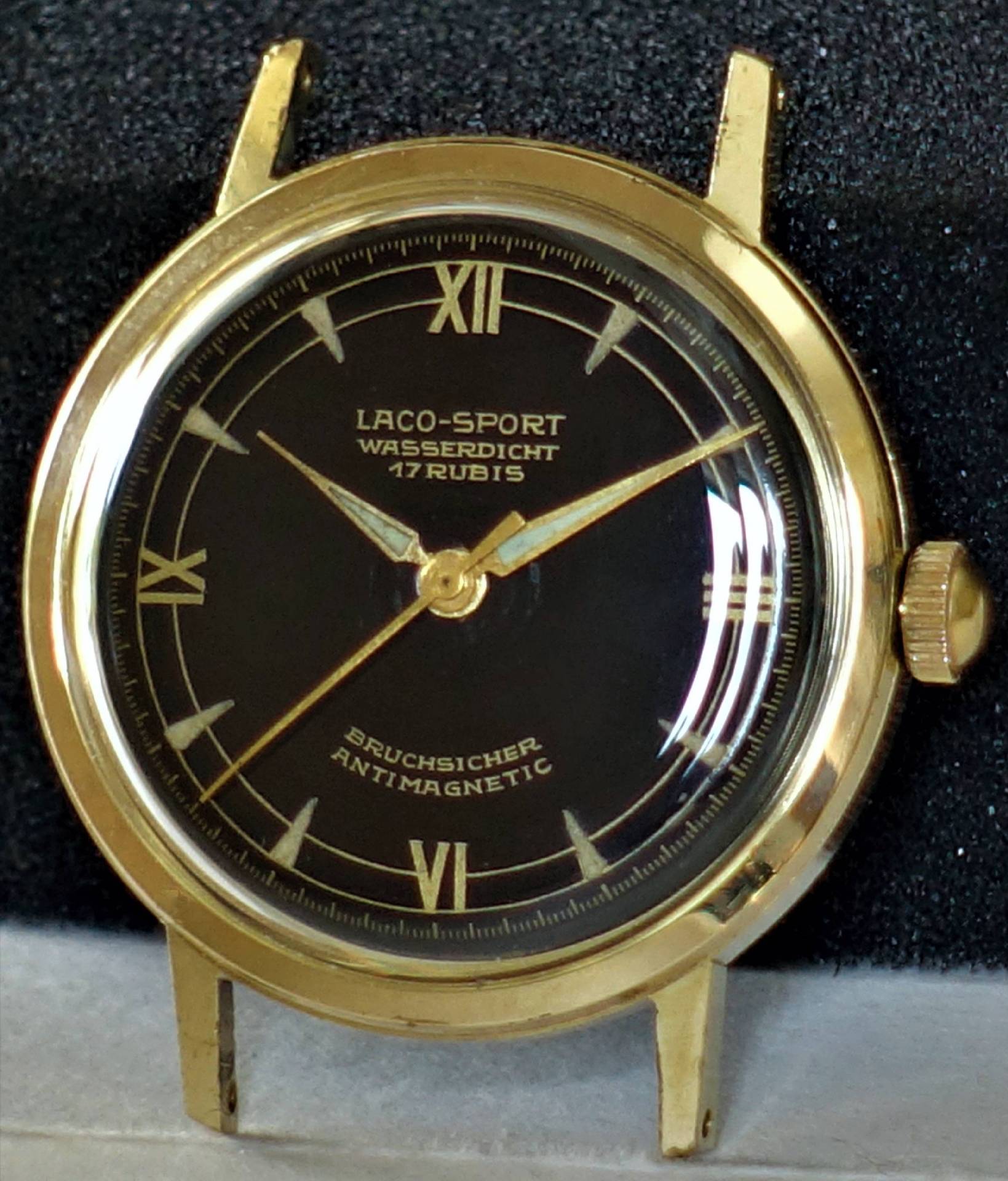 Goldfarbene Armbanduhr mit schwarzem Zifferblatt und römischen Ziffern.