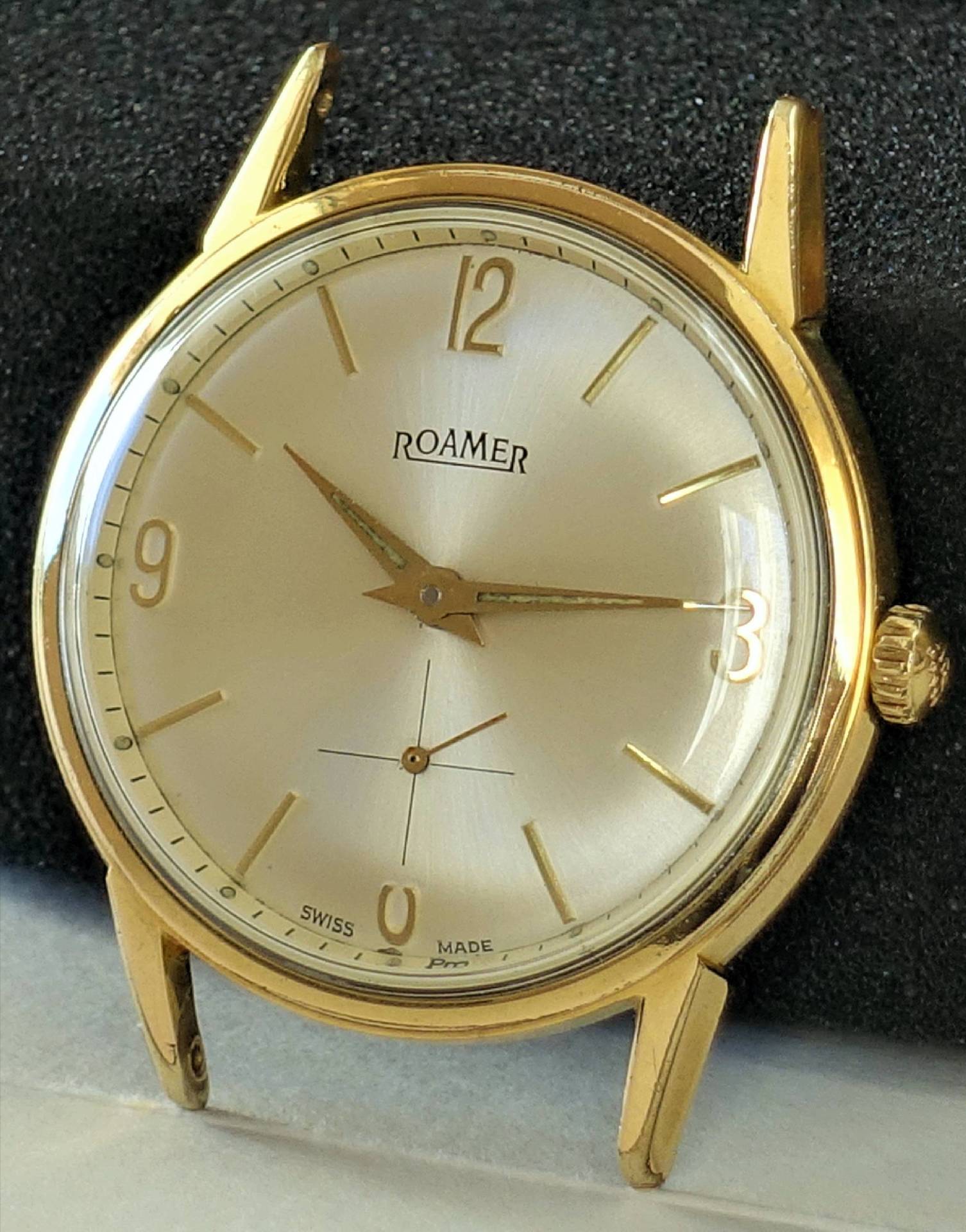 Goldfarbene Armbanduhr mit hellem Zifferblatt und goldenen Zeigern, Marke Roamer.