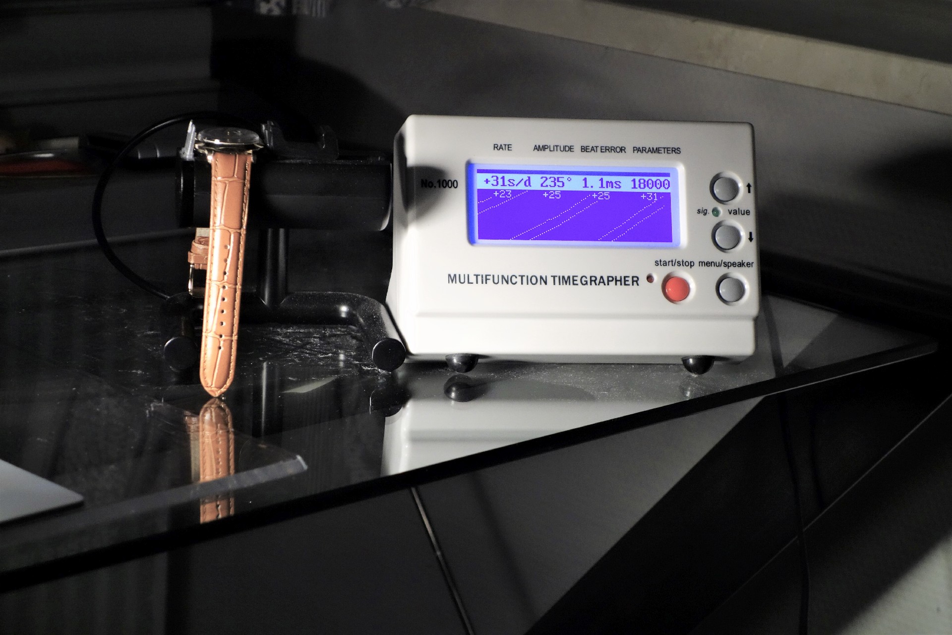 Weißes elektronisches Messgerät zur Überprüfung von mechanischen Uhren mit digitalem Display.